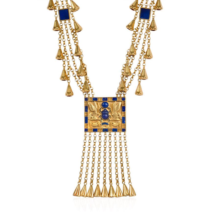 An Egyptian revival style sautoir comprised of reeded chains and rectangular lapis panels with fluted pendants throughout and a central bas relief panel depicting a lapis scarab flanked by wasps, in 18k gold. Marked FM 80, MN