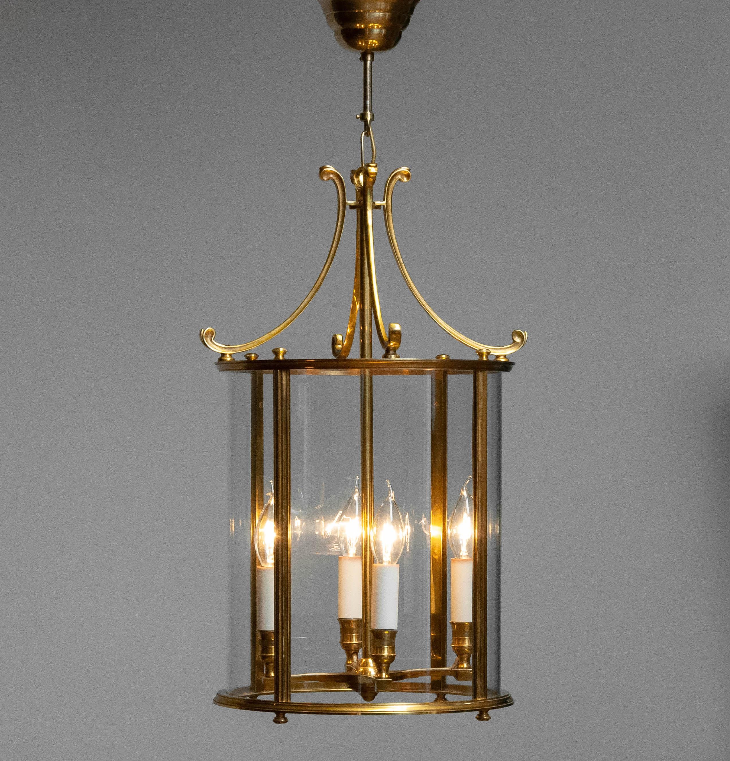Lanterna in ottone con vetro curvo proveniente dalla Francia, 1970. Questa elegante lampada a sospensione presenta un design classico con una struttura in ottone lucido e pannelli in vetro curvo, creando un look senza tempo. È dotato di prese a vite