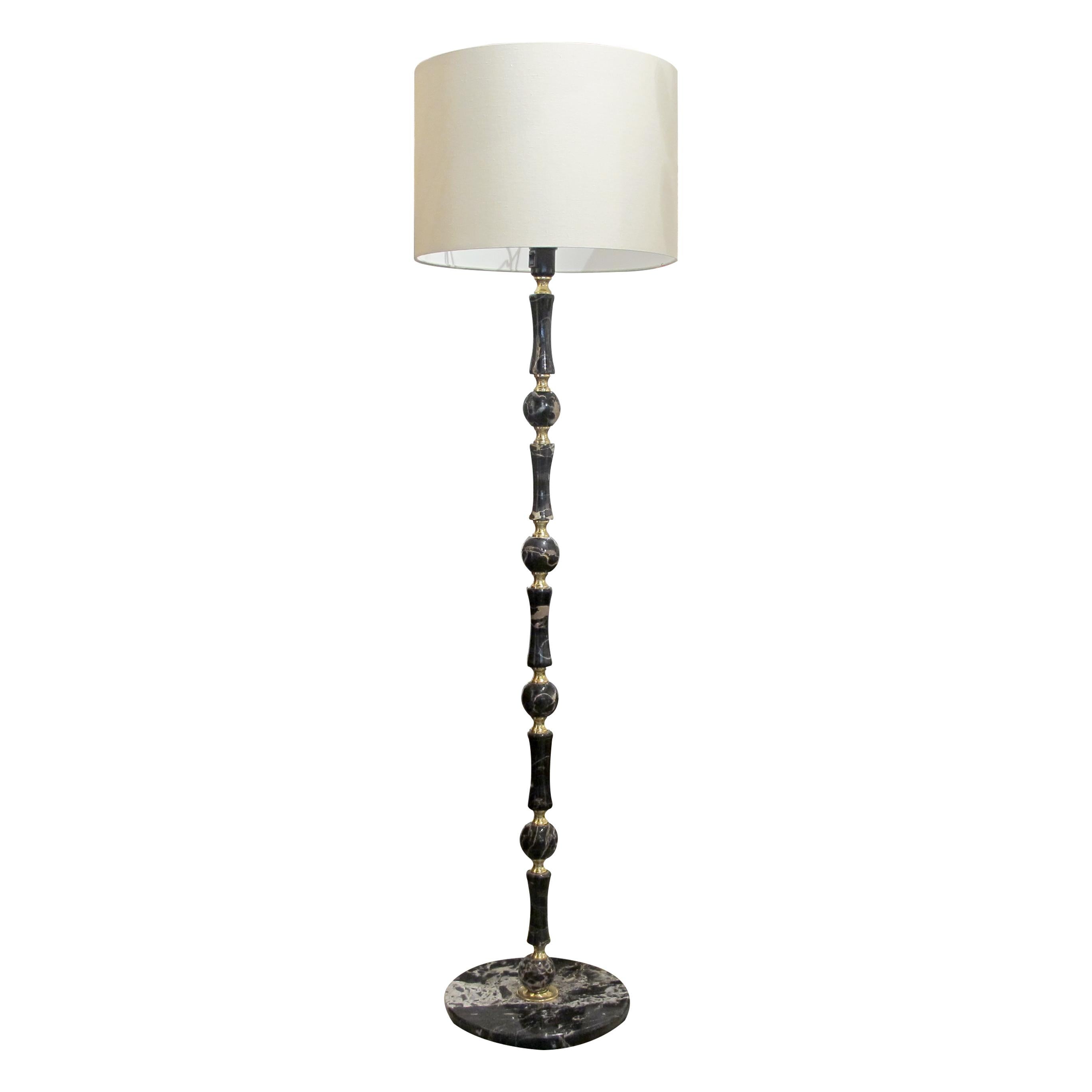 Pareja de lámparas de pie suecas vintage de finales de los años 70, que muestran una llamativa combinación de mármol negro y latón. Cada lámpara presenta una columna alta y elegante con un diseño escalonado, compuesto por formas orbitales y