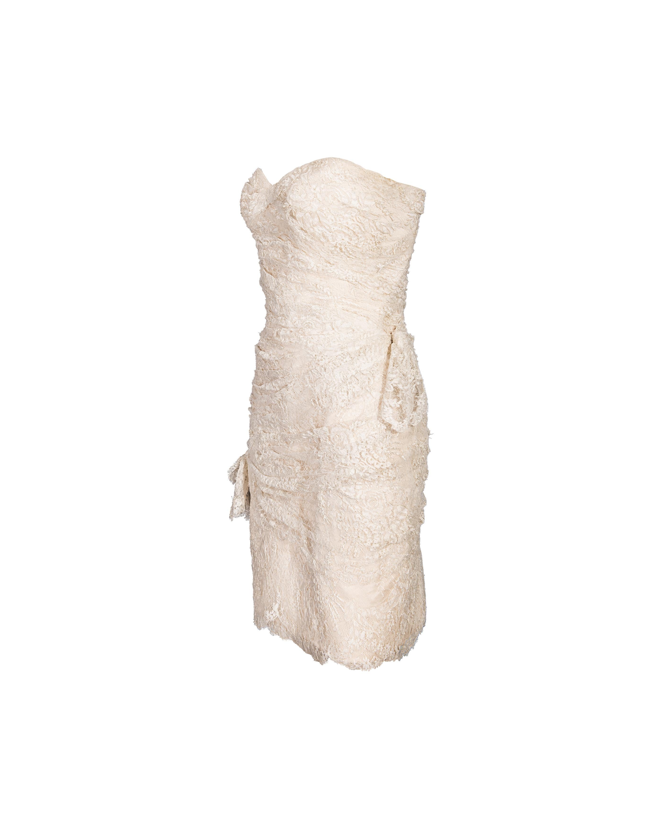1970's Emanuel Ungaro ecru strapless lace sheath mini dress. Fitted strapless mini dress with gathered, draped lace throughout and nude lining. Small bow details. Concealed back zip closure. This piece has been taken to professional couture cleaner
