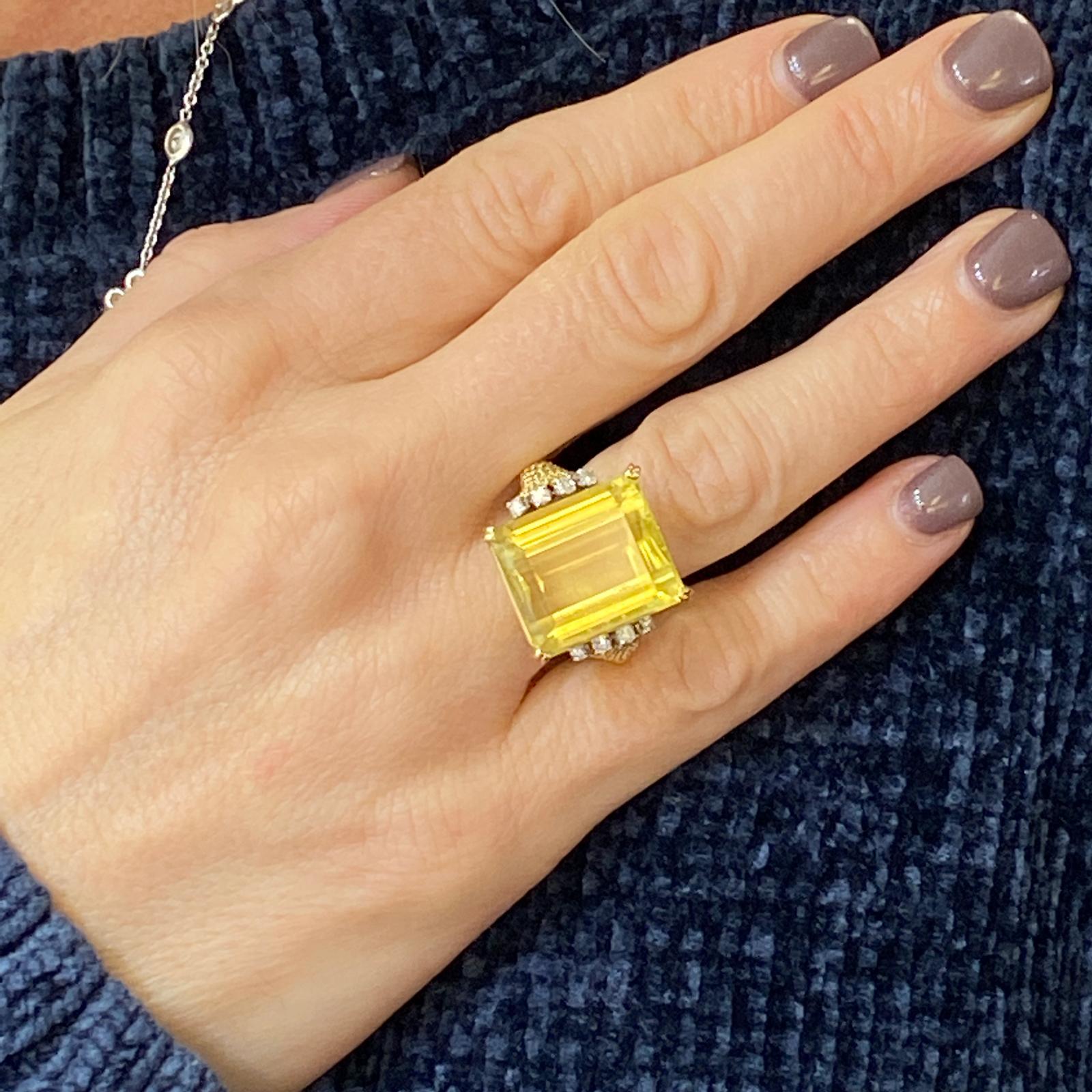 1970's citrine diamond cocktail ring fashioned in 18 karat yellow gold. The emerald cut lemon citrine weighs approximately 15 carats and features a beautiful bright yellow color. The citrine is surrounded by 8 round brilliant cut diamonds weighing