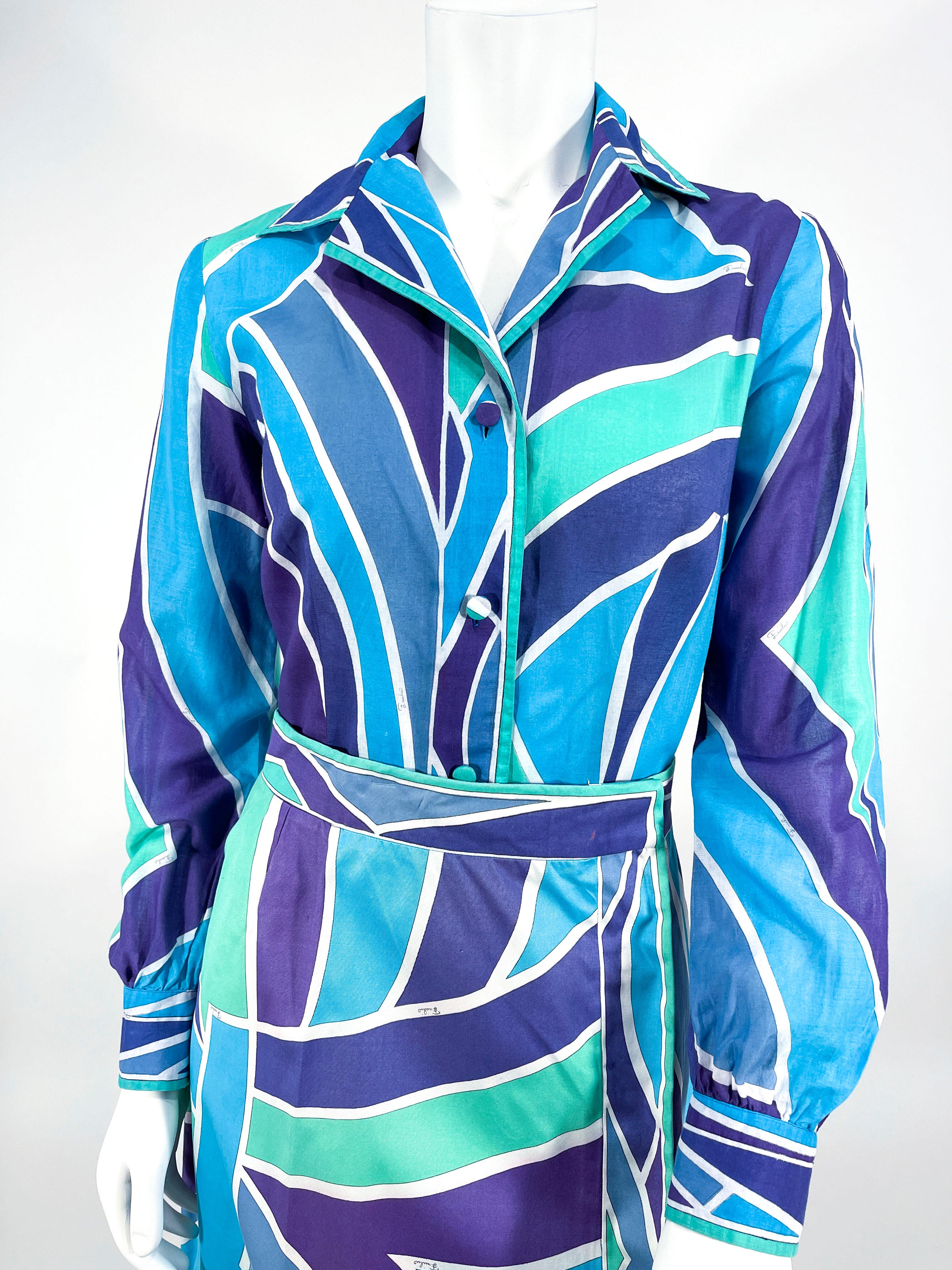 1970s Emilio Pucci geometric printed cotton two-piece set. The geometric printed features jewel tones of violet, blue, green, and whites. The sheer cotton shirt has a butterfly collar with long cuffed sleeves and boarder prints along the edges. The