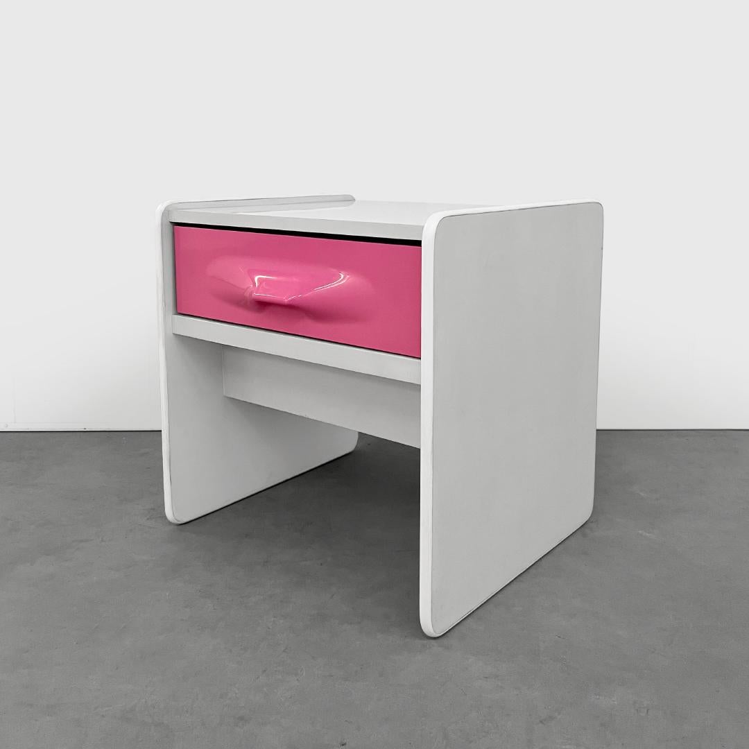 This vintage end table was designed by Giovanni Maur for Treco circa 1970 and is reminiscent of Raymond Loewy's DF2000 series. This piece features the less common pink ABS molded drawer front and functions as a bedside table or end table. In good