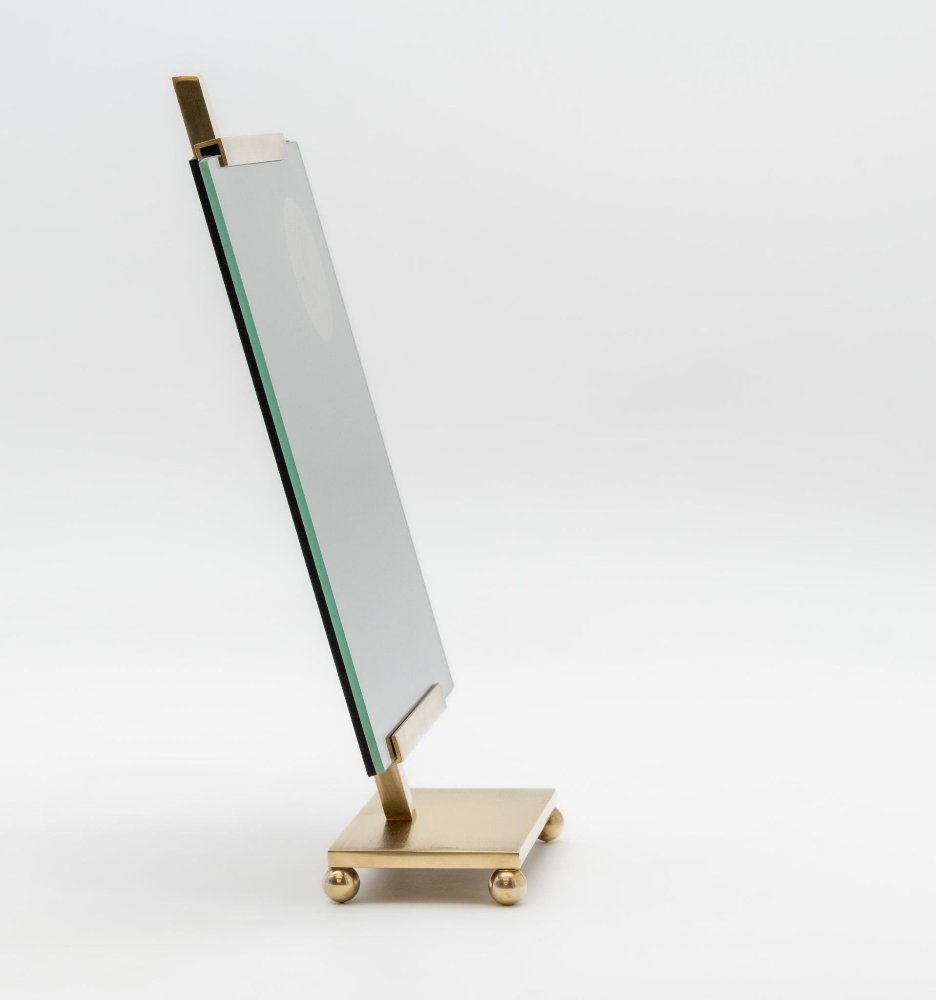 A neat solid brass photo frame on an angled base with four balled feet. English. Circa 1970. Labelled: 'Fine English Brass' & 'Made in England'.

In very good condition with no damage. The brass has been polished. 



