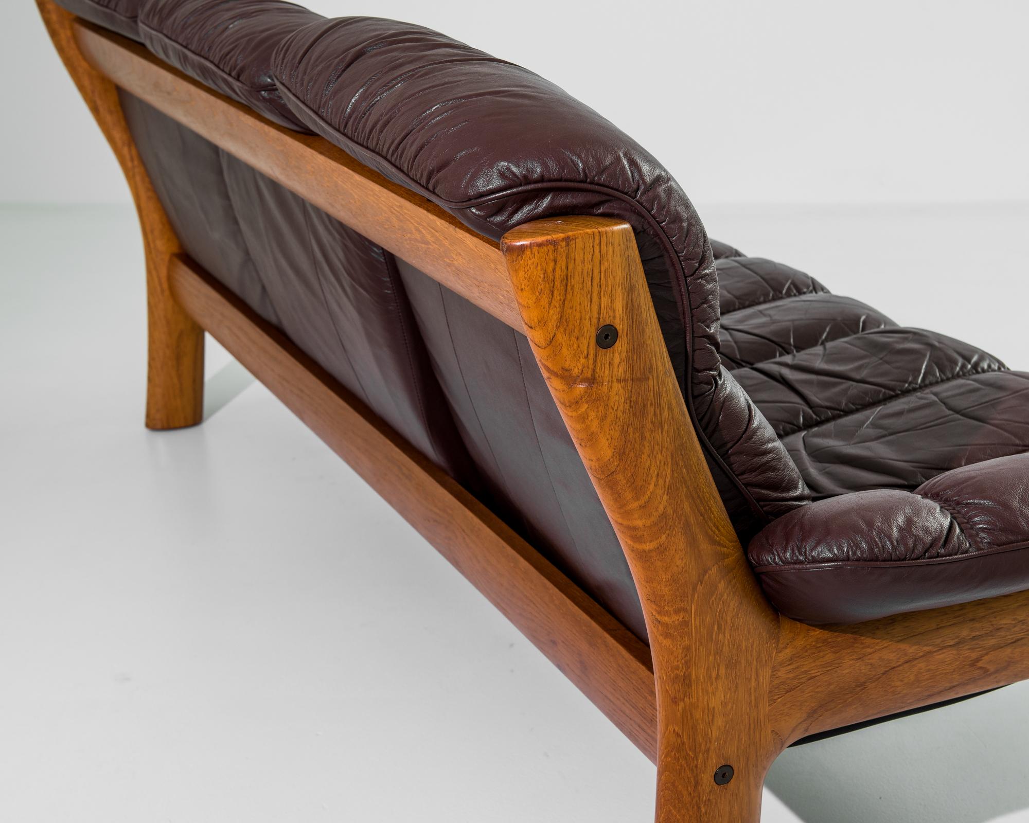 A 1970s sofa by Norwegian furniture designer Ekornes. Bright teak and rich oxblood leather create an ambience of composed luxury. The rounded curves of the teak frame echo the organic form of tree branches, while the sophisticated segmentation of