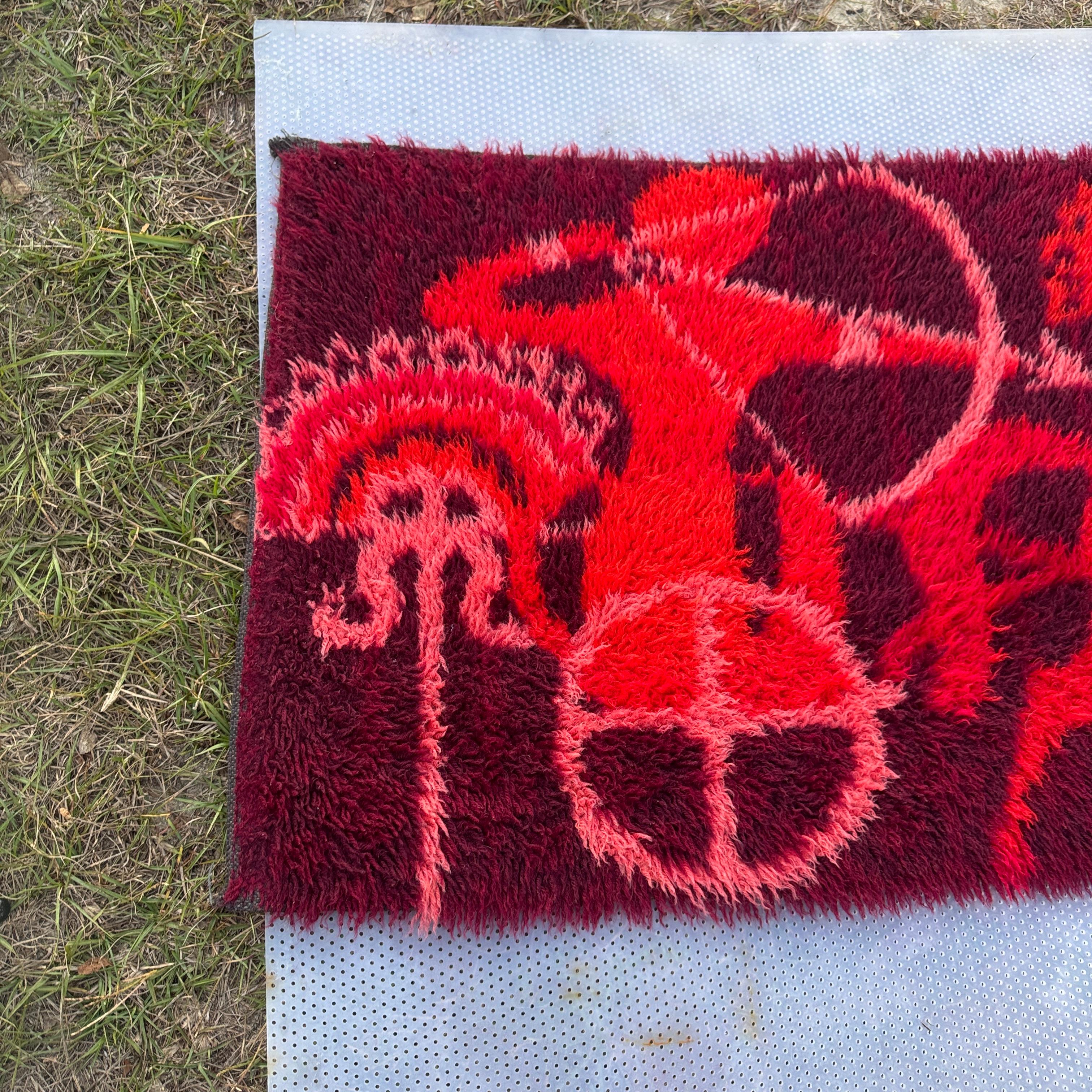 Late 60s early 70s rya shag rug in pink and red tones of a scene reminiscent of the Etruscan period. A figure on a horse and chariot with a bow and arrow aimed at a target off in the distance. This rug’s shape works well as a runner down a short
