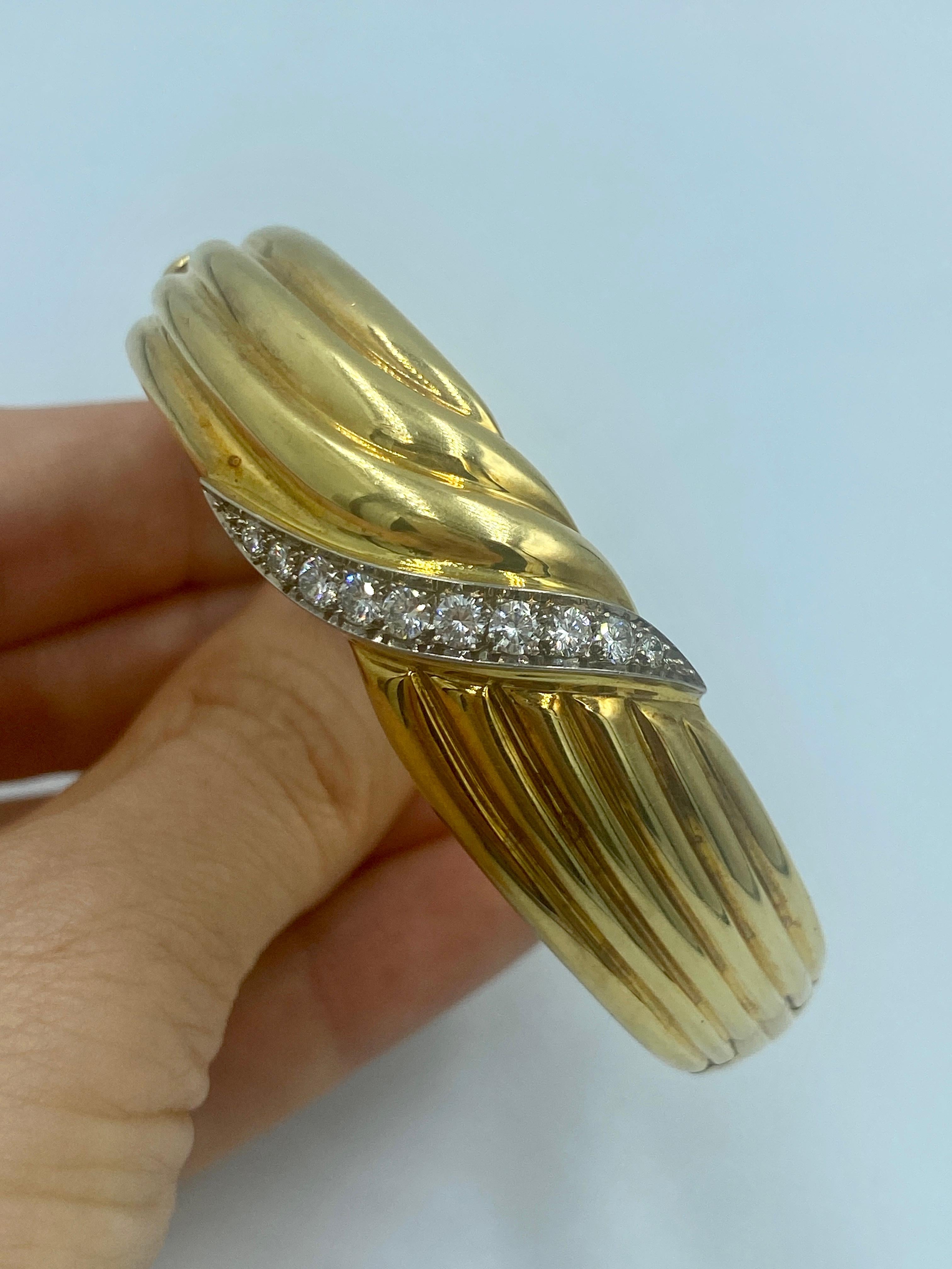 This elegant 1970s European made 18k gold bangle has a swirl design and is adorned with a swirl of approximately 1 carat of diamonds. The inner circumference of this bangle measures 18cm.