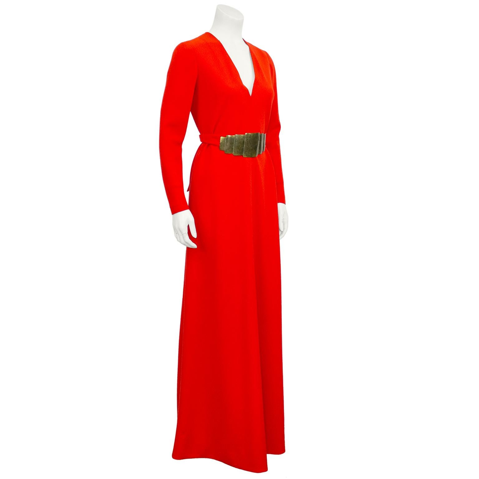 1970's sophisticated flame red rayon crepe V-Neck gown with hand made gilt metal waist ornament. This dress is one of a small selection of pieces from the closet of a renowned Hollywood musical celebrity. She was part of a performing family and her