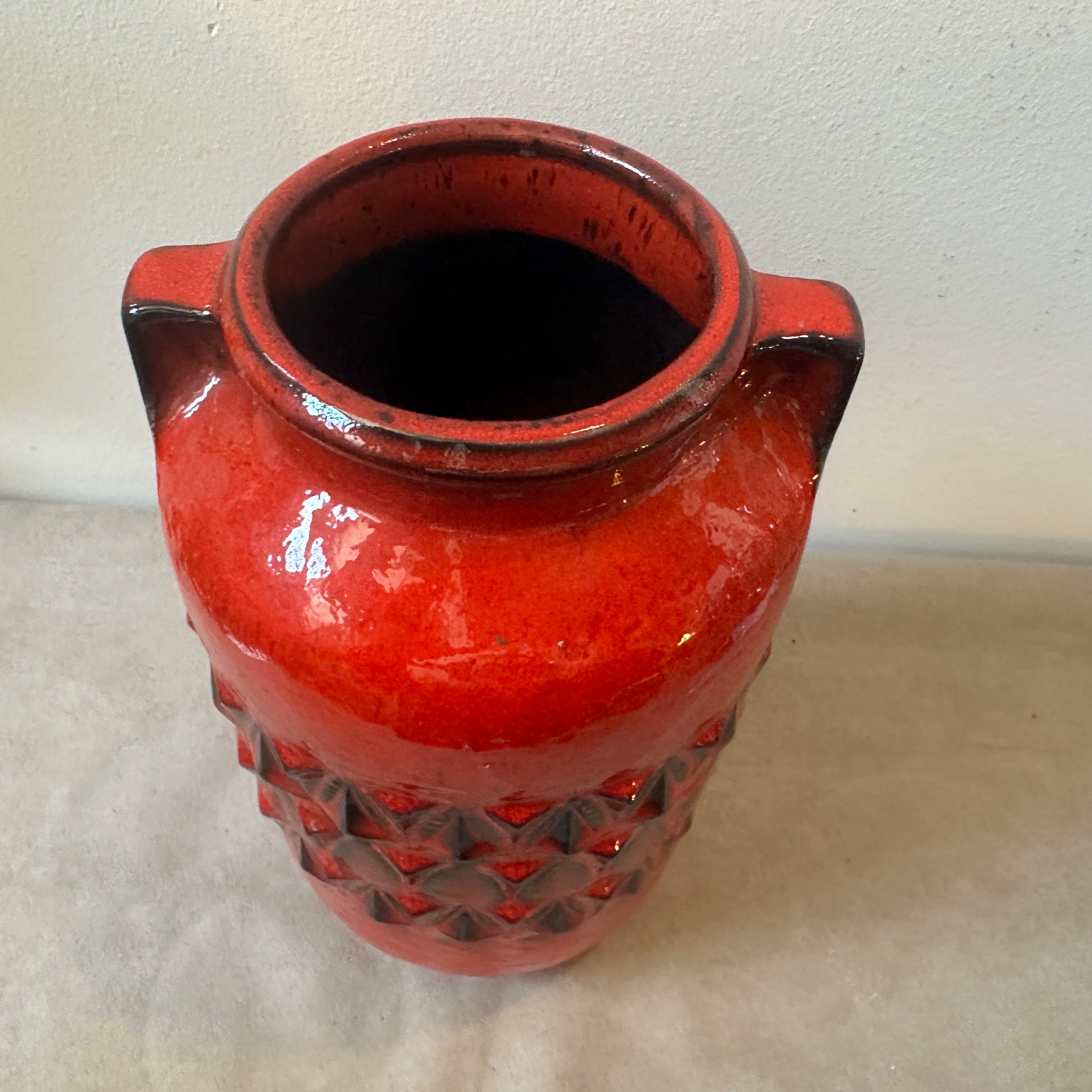 Diese deutsche Vase aus roter und schwarzer Keramik ist ein eindrucksvolles Beispiel für die Designästhetik dieser Epoche, die sich durch kräftige Farben, strukturierte Oberflächen und skulpturale Formen auszeichnet. Er dient sowohl als funktionales