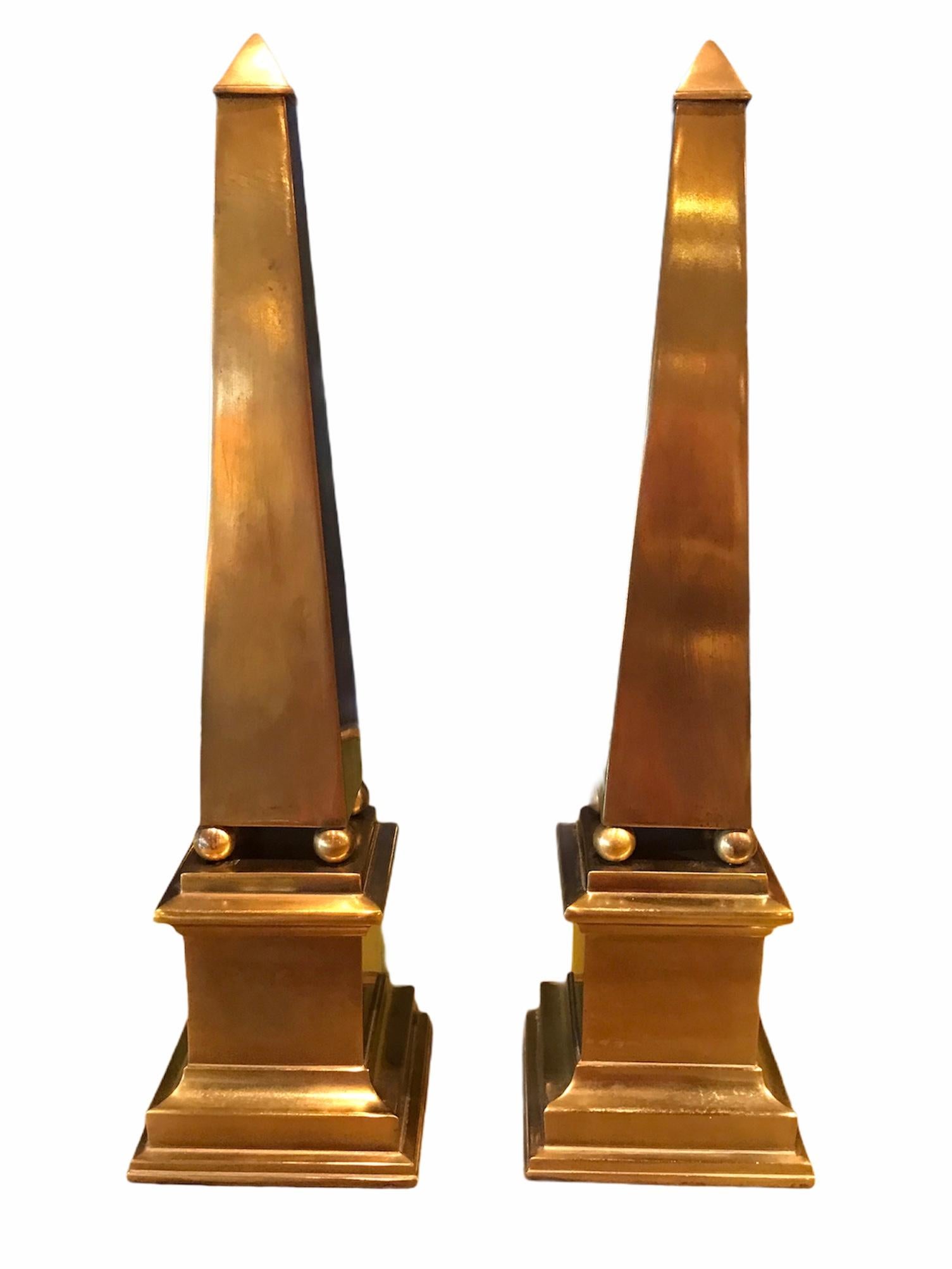 Wonderful pair of brass Obelisks in a smooth modern style. Inspired by French Empire obelisks, this 1970s pair have a rich patina. Some age related spotting along the plinth base in the back (see pics). Felt lined bottom. Great for the mantel or