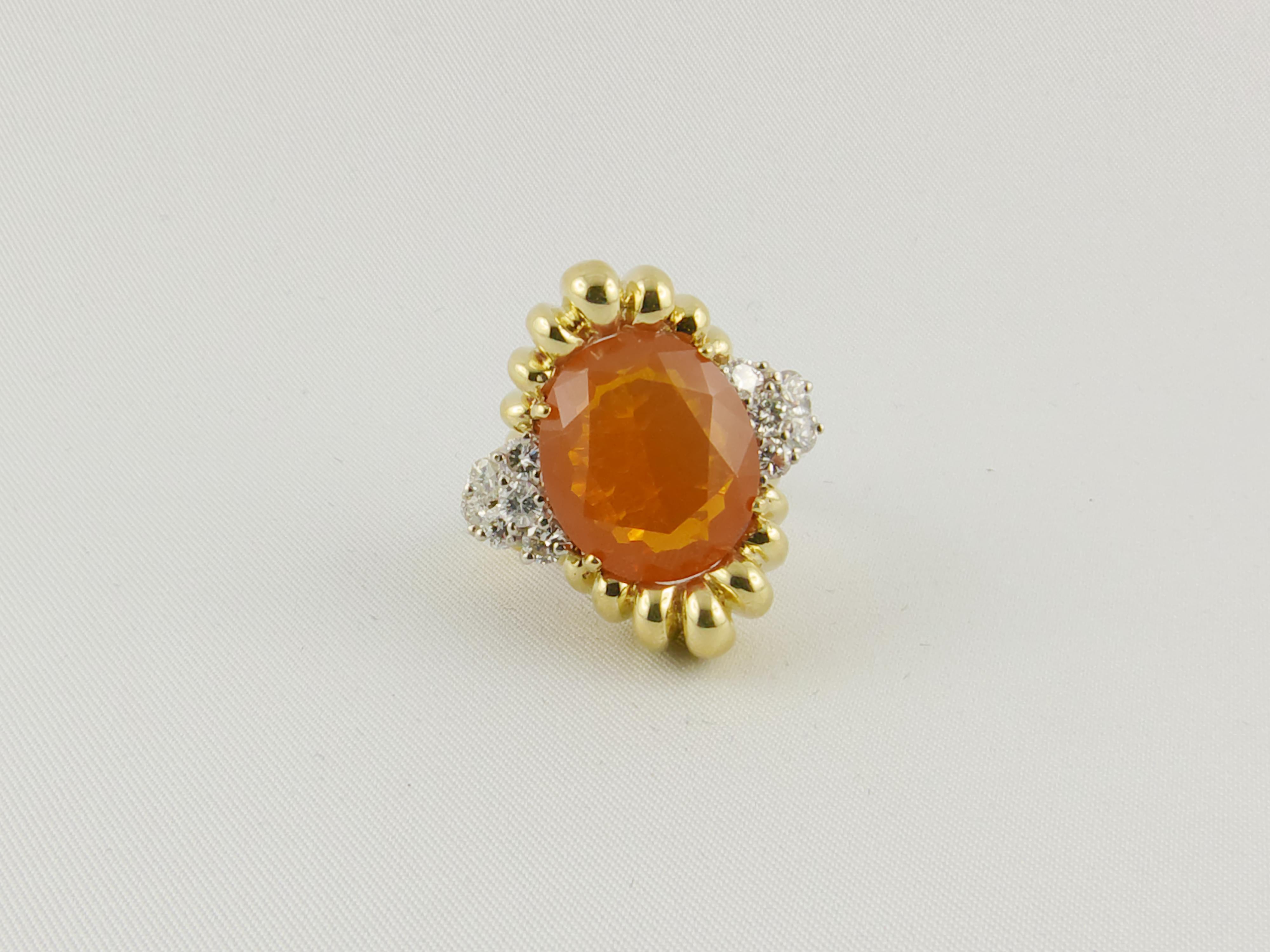 1970s unconventional and intriguing exquisite piece of jewelry  composed of a central  bright- orange background color,  semitransparent faceted Fire Opal, with play-of-color, set in 18kt Yellow Gold. 
Twelve round-cut Diamonds (approx 0.80cts)