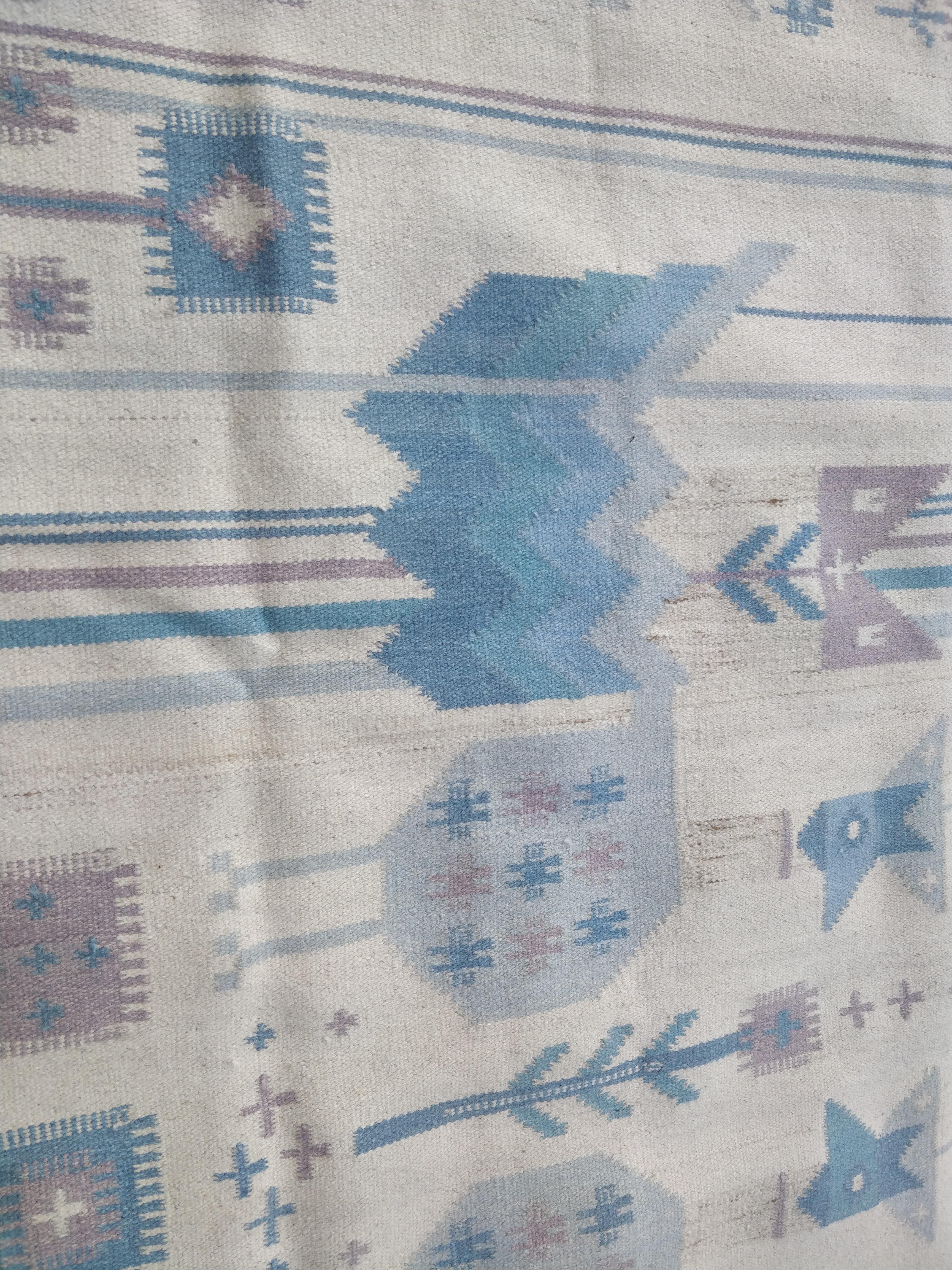 Cette tapisserie en laine présente un motif composé d'oiseaux stylisés et de fleurs dans des tons bleus. Dans le coin inférieur droit figurent les initiales du designer, NE (Németh Éva). Depuis les années 1970.

Éva Németh (1930-2019) était une