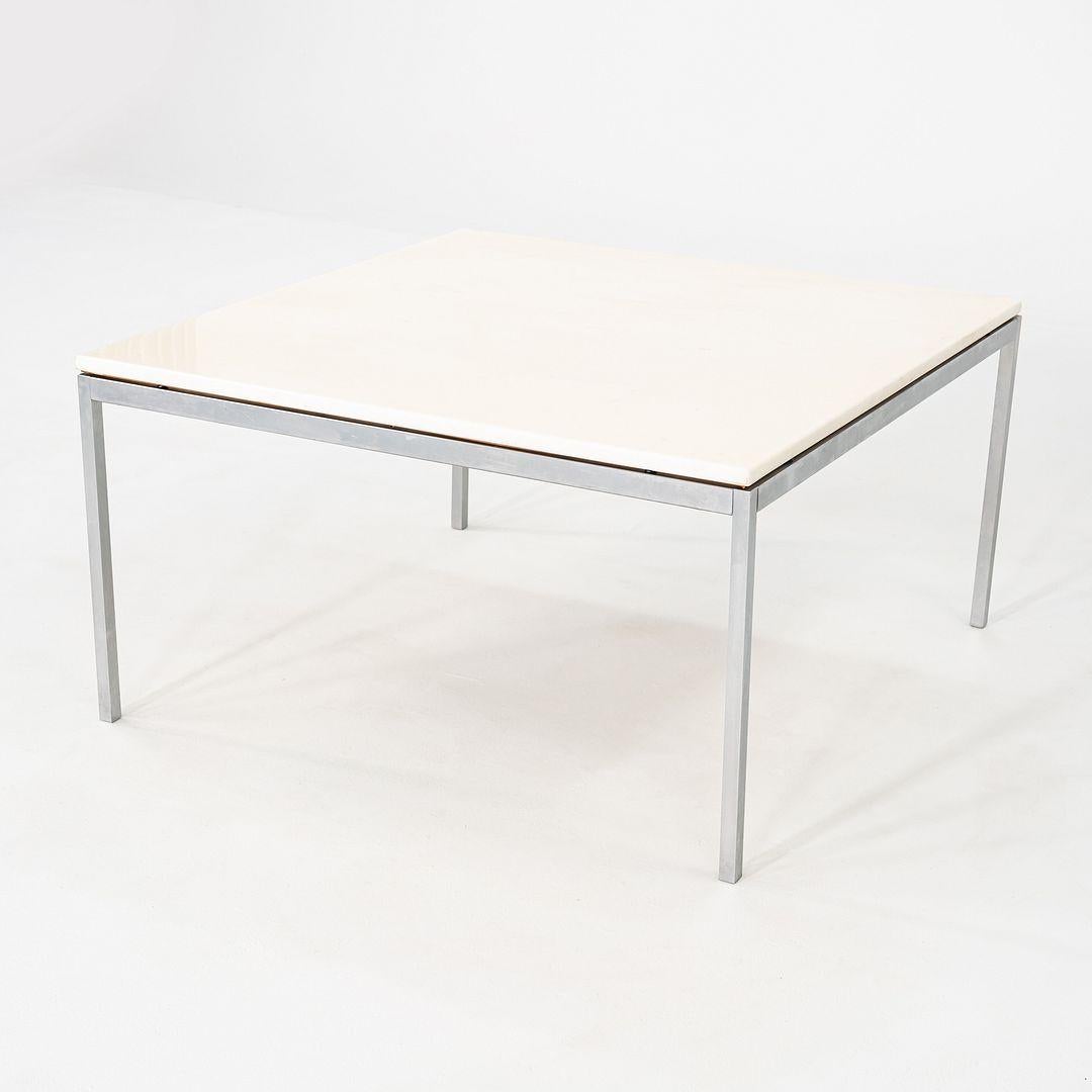 Il s'agit d'une table basse ou d'appoint carrée, conçue à l'origine par Florence Knoll pour Knoll en 1954. Cet exemplaire a été produit aux États-Unis dans les années 1970. La table présente un plateau en marbre blanc, soutenu par une base