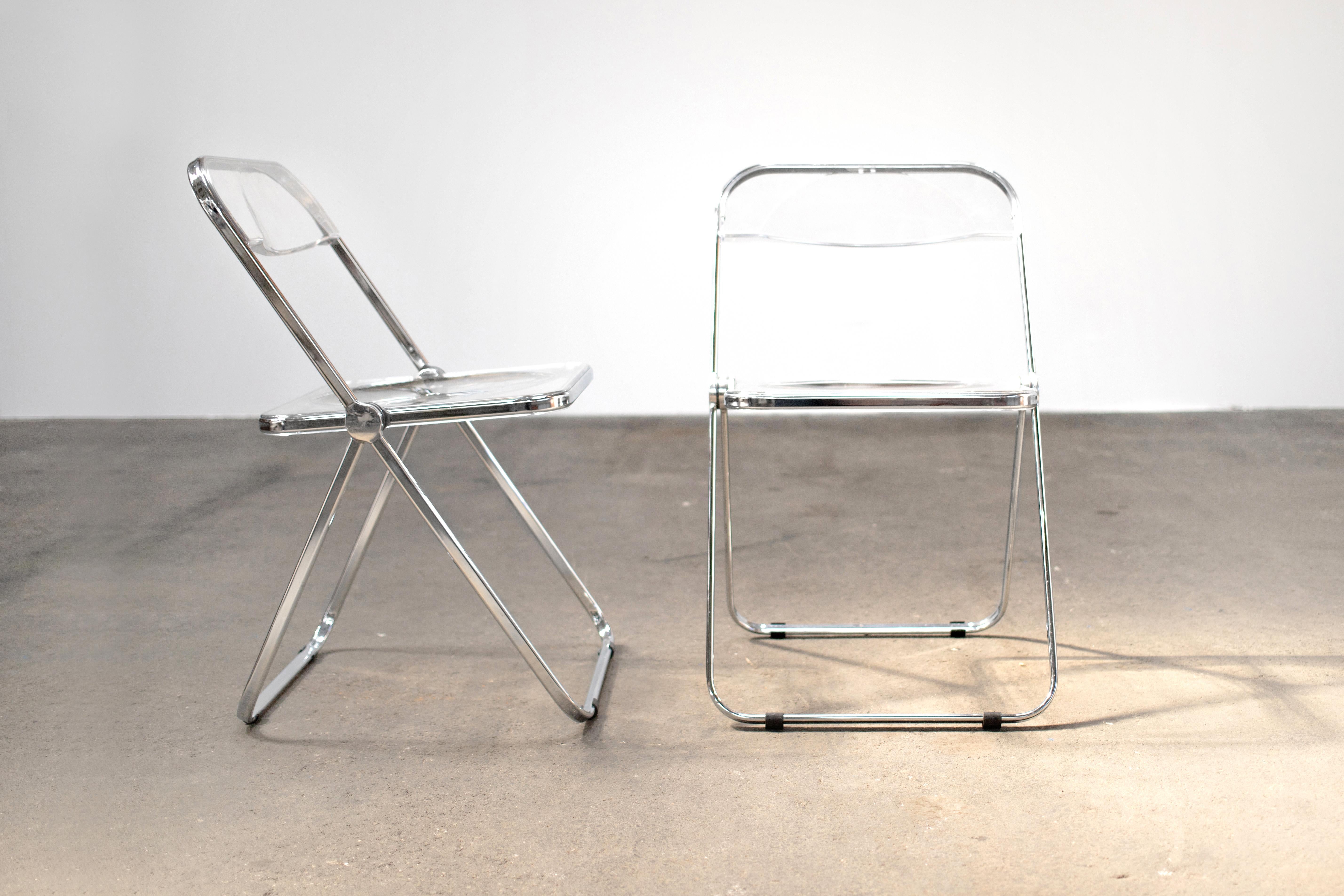 Superbly preserved pair of Space Age chrome and transparent lucite folding chairs designed by Giancarlo Piretti for Castelli, Italy. 

With steel frame, seat and back in clear lucite, it represents the realization of “democratic design” and is