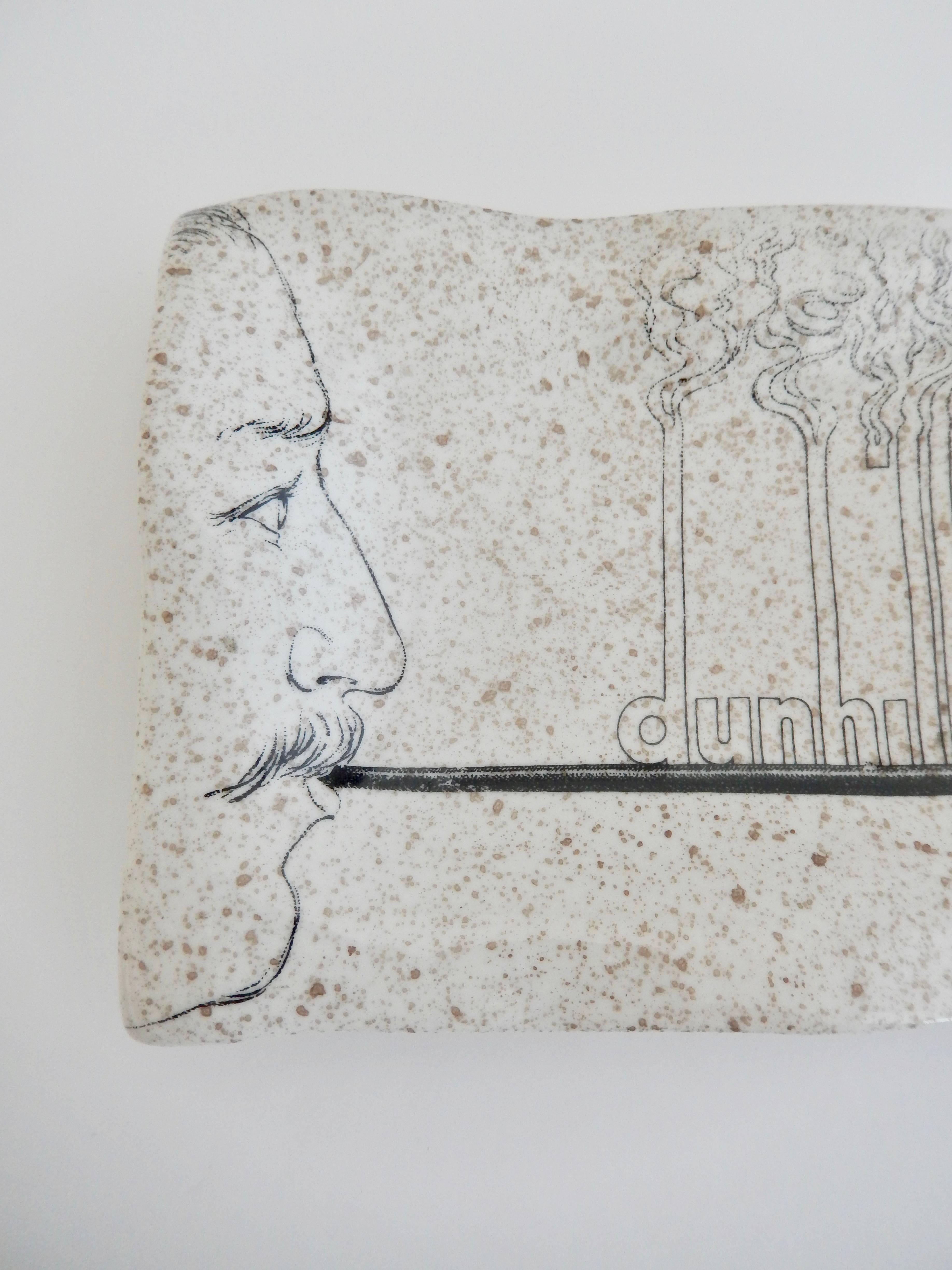 A ceramic tray from 1978 by Piero Fornasetti for Dunhill, New York, depicting a self-portrait of the artist holding a paintbrush. An original graphic design, probably used for promotional purposes. Marked “EXCLUSIVE FOR DUNHILL NEW YORK”. A similar