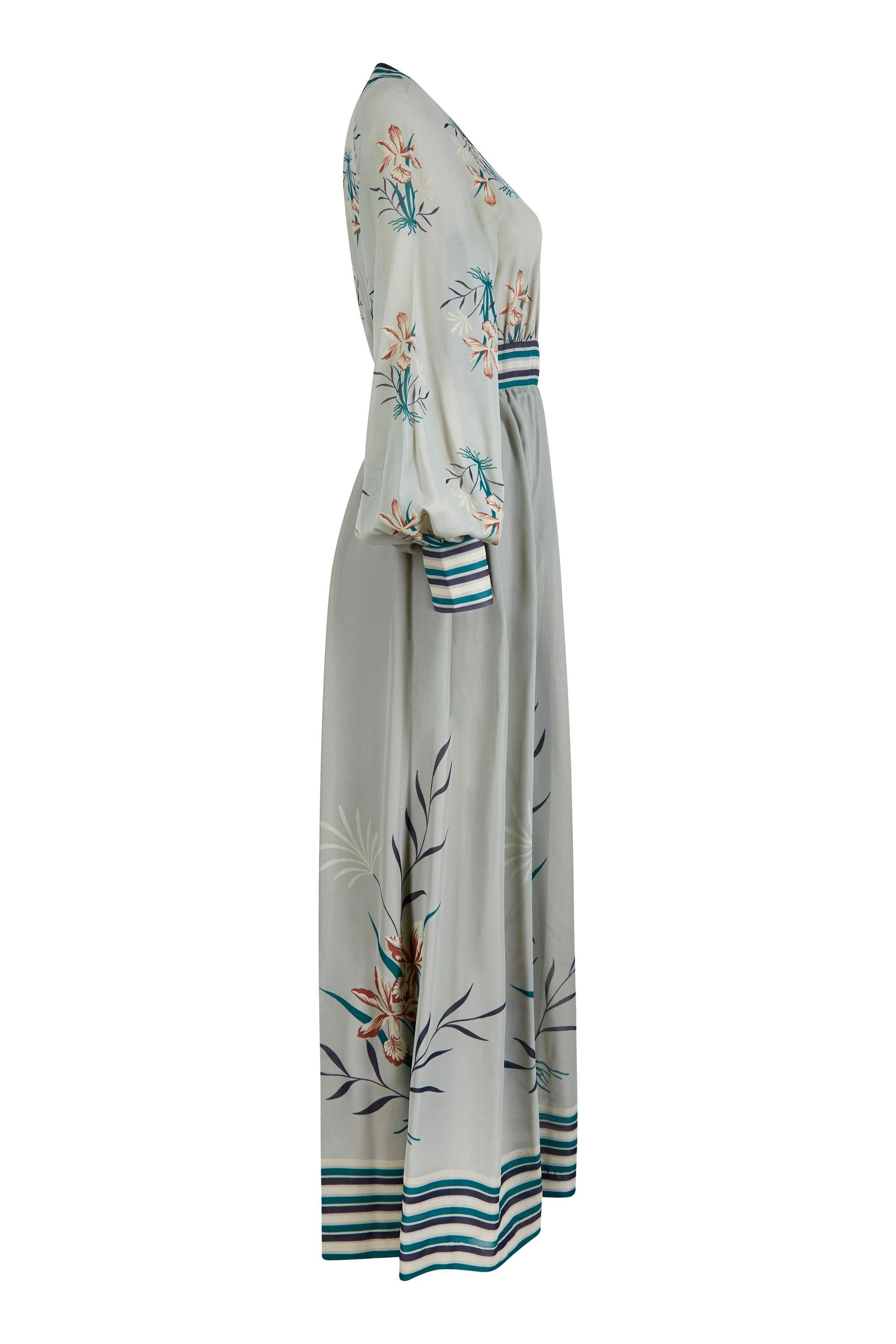 This beautiful 1970s Frank Usher printed chiffon maxi dress in seafoam blue green is elegant, feminine, and in excellent vintage condition. The dress features a wrap over bodice which is secured across the bust with concealed hook and eye fastenings
