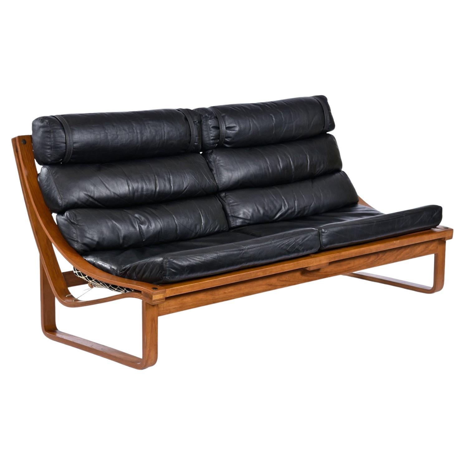 Low profile meets high comfort without compromise with this T4 Sofa. This particular piece is an early 70s release, and is designed by Fred Lowen for Tessa Furniture. Curved, bent-ply teak rails are the ideal frame to suspend the gorgeous leather