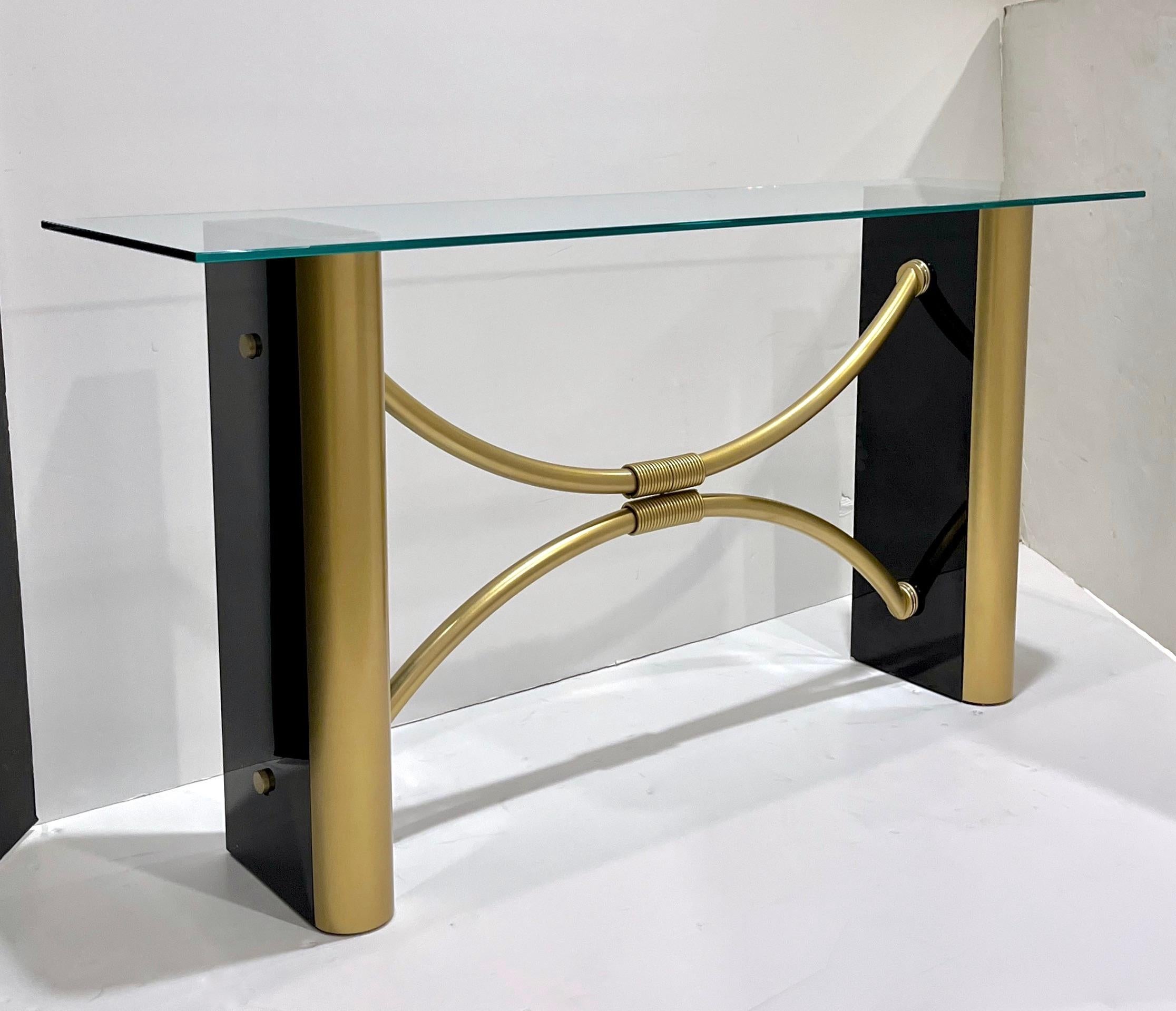 Unterstreichen Sie die Eleganz Ihres Wohnraums mit diesem exquisiten Konsolentisch aus Glas und messingfarbenem Lack, der durch seine geschwungenen Beine besticht. Das schlichte Design und die luxuriösen Materialien machen dieses Stück zu einer