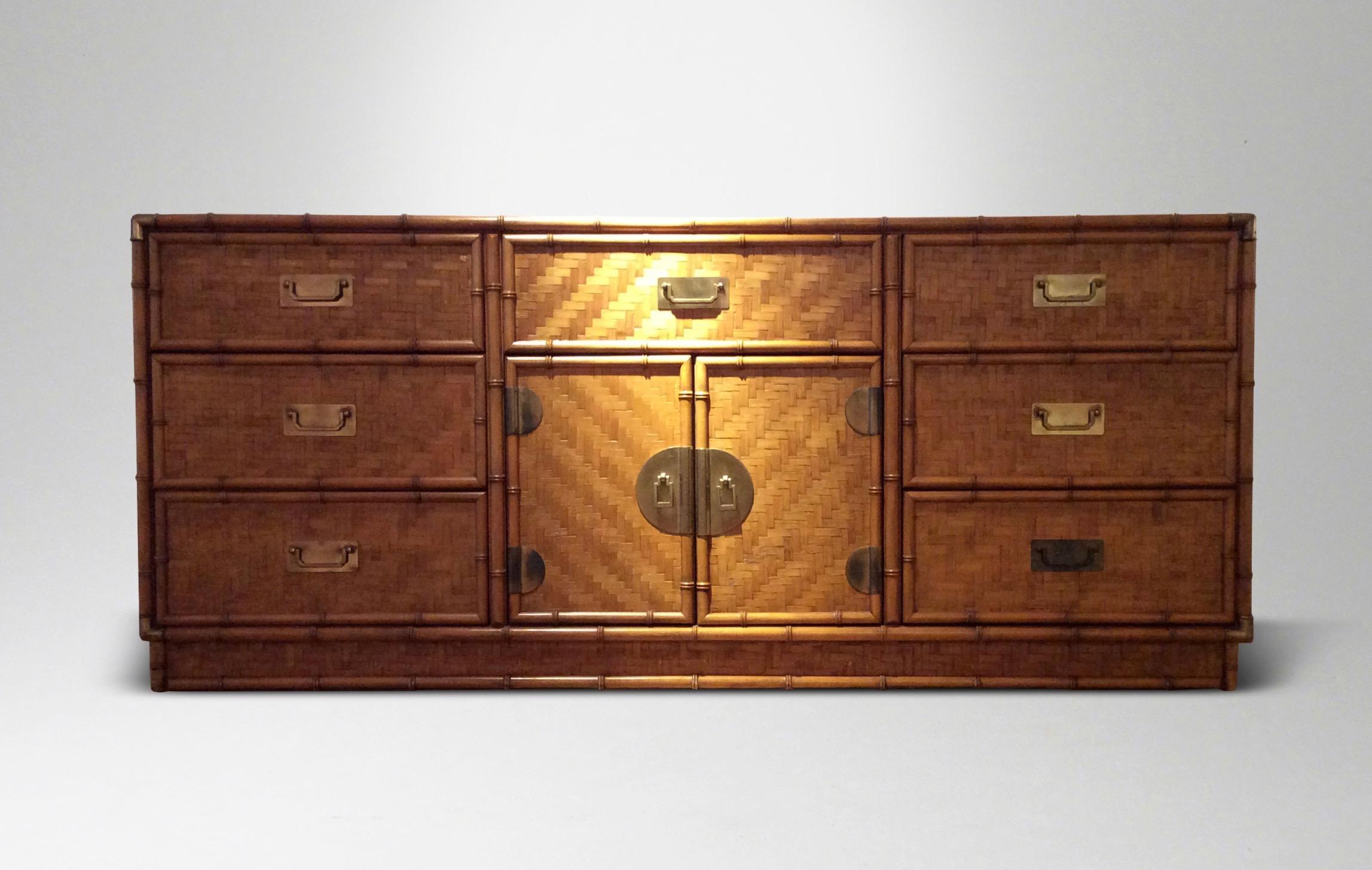 Woven split bamboo panels banded by bamboo canes, internal shelving and drawers, with brass mounts, door pulls, and corners cast as bamboo.