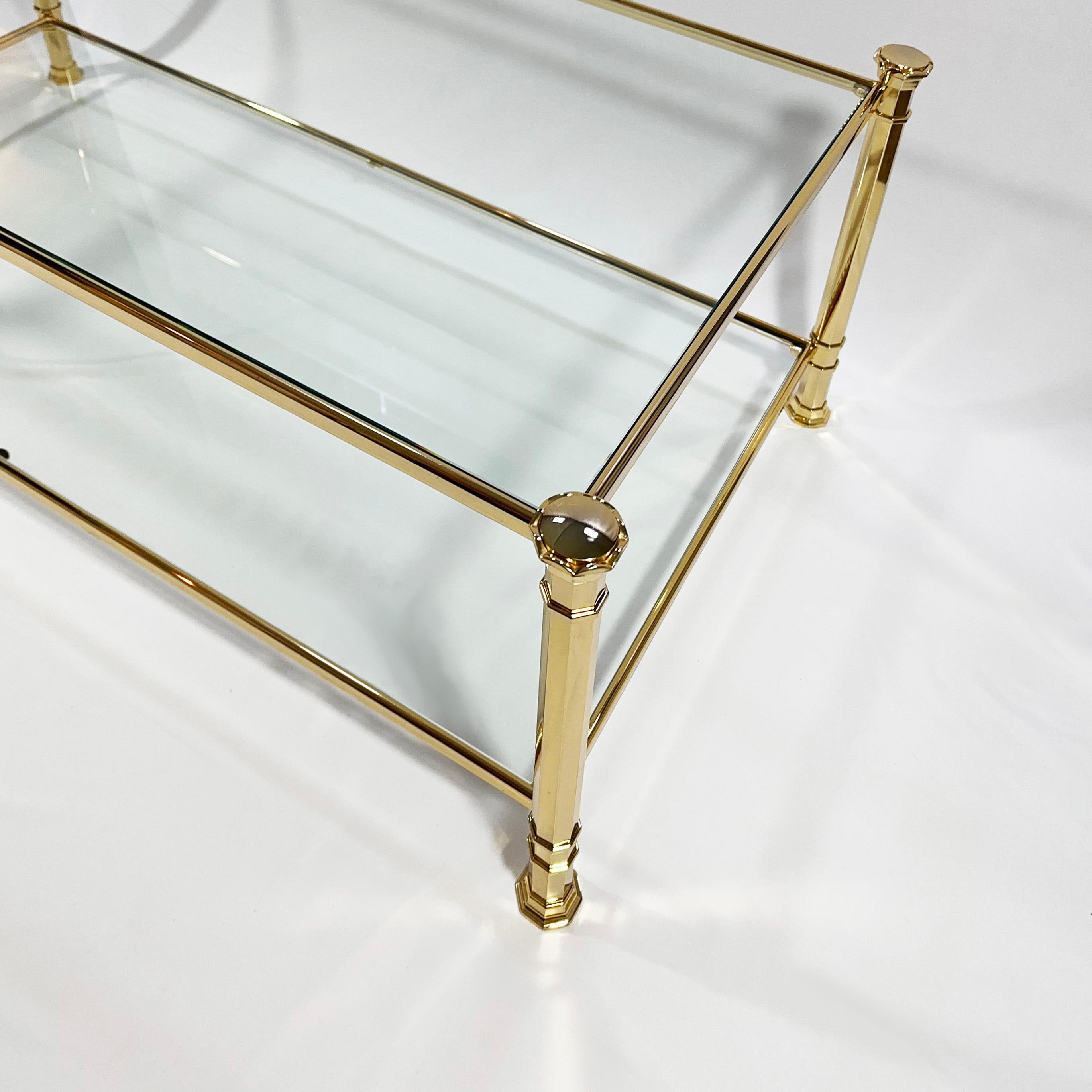 Discover the epitome of 1970s chic with this French neoclassical coffee table, a harmonious blend of sturdiness and grace. The octagonal, pillar-like legs and slender brass frame reveal its neoclassical-style design elements, supporting two tiers of