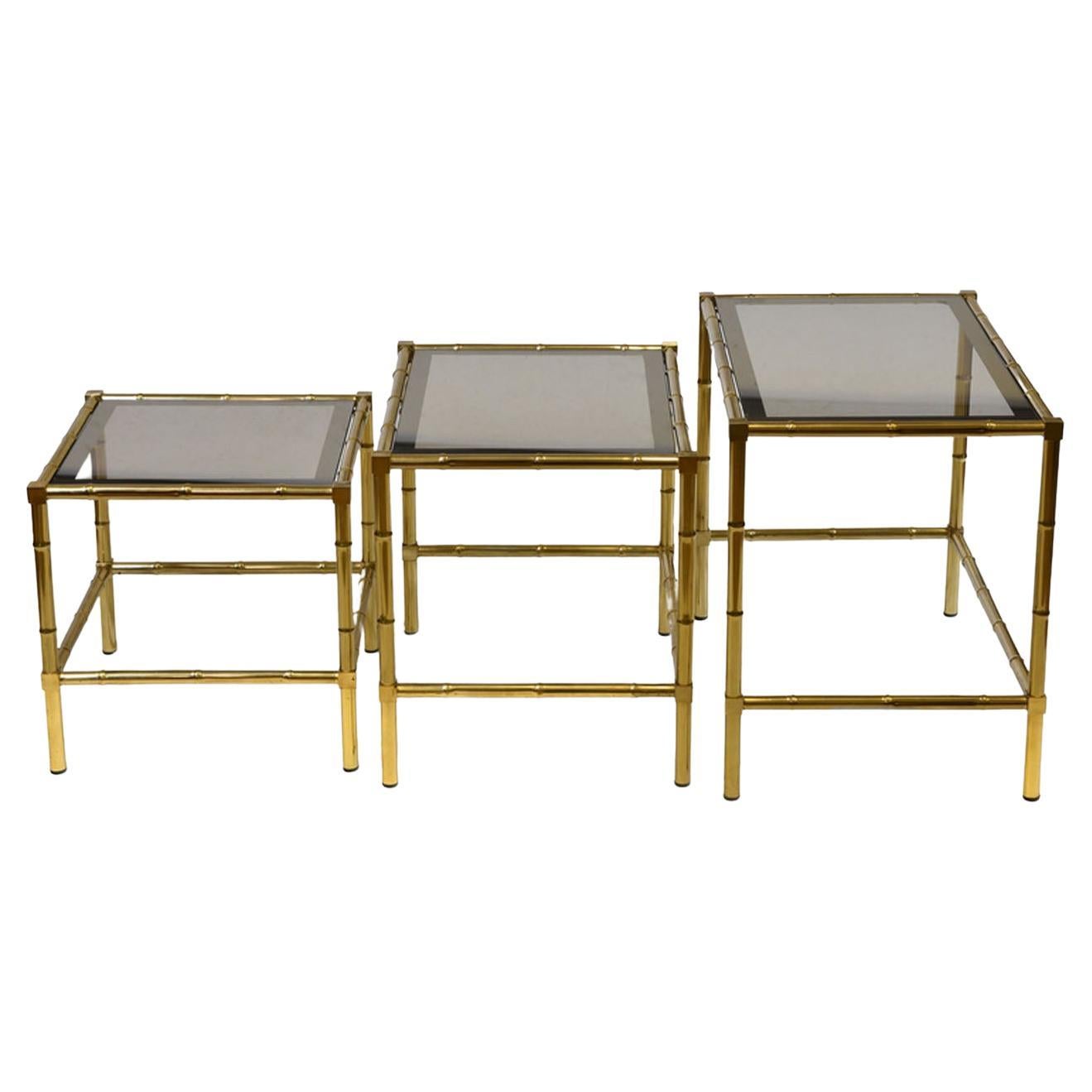 A vintage French brass plated faux bamboo nest of three tables with smoked glass inset in the Jacques Adnet manner. Circa 1970.

The tables are in good condition for their age, showing some light marks to the finish in places. The lightly smoked
