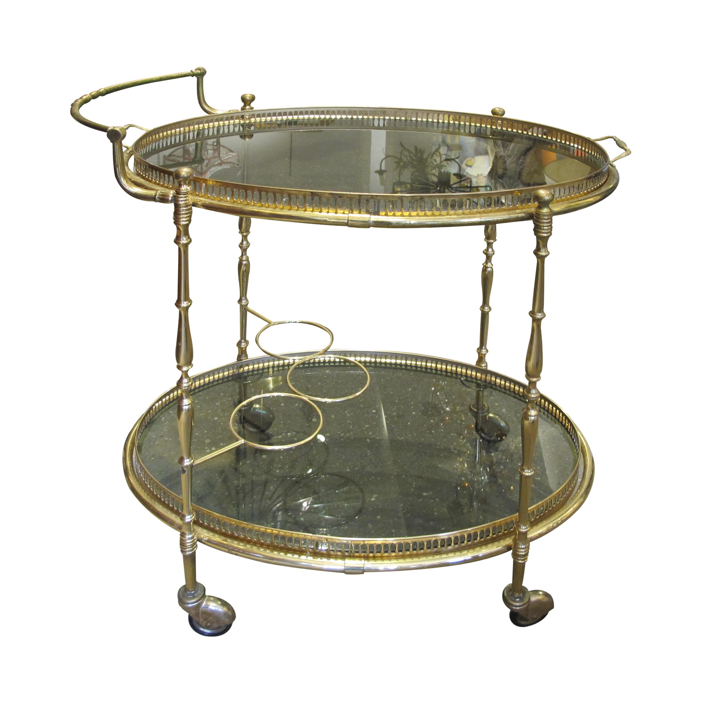 1970s well-made brass serving two-tier bar cart/trolley in good condition presented on four directional wheels. The original smoked glass is typical from the mid-century period, the top tier is a removable tray with brass handles. 

Size: H62 cm x
