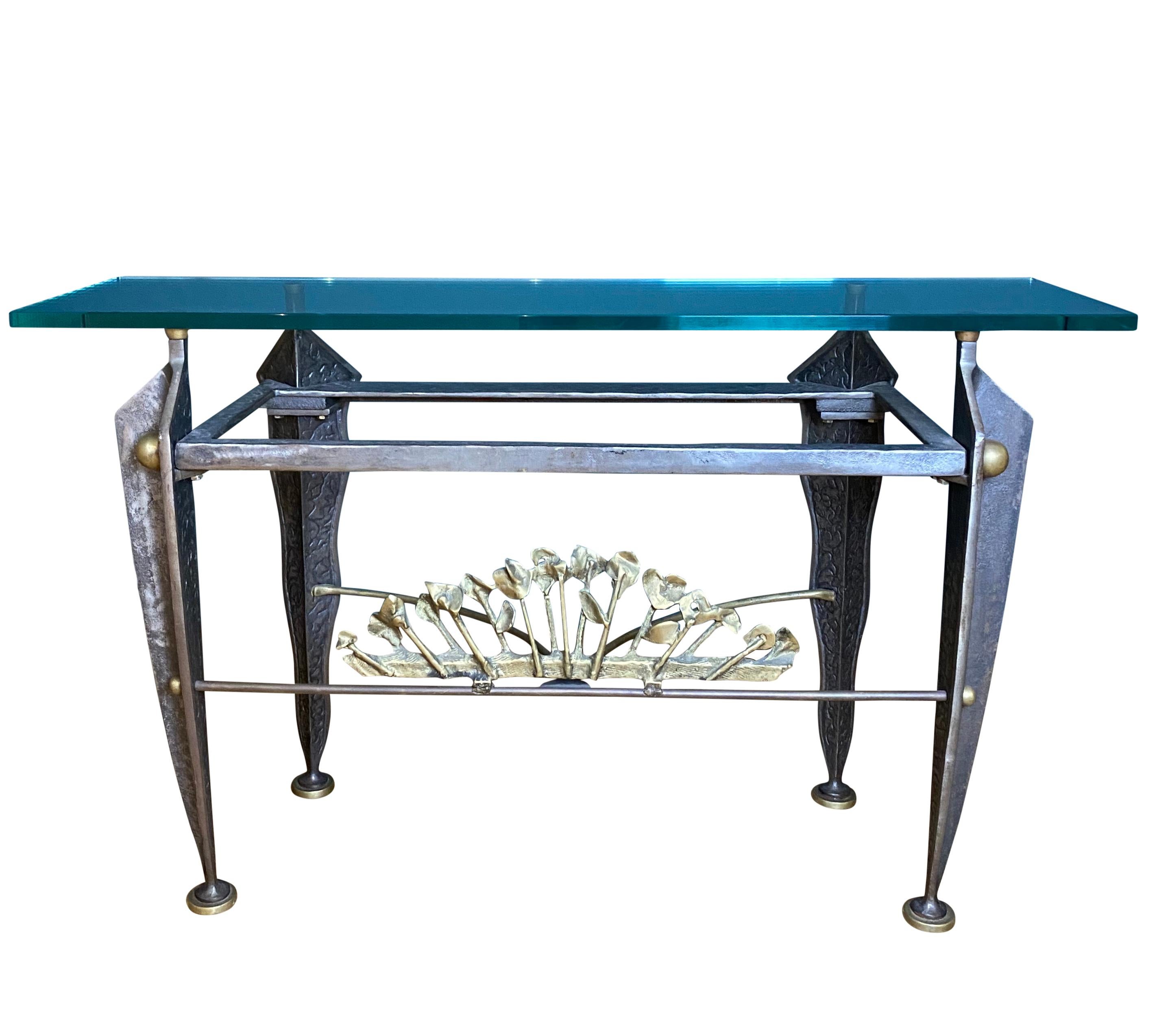 A heavy sculptural console table featuring a fan of lilies in gilded bronze, supported by four hand hammered legs with exceptional detailing.

Measures: Glass top W: 125cm, D: 34cm, thickness: 2cm.