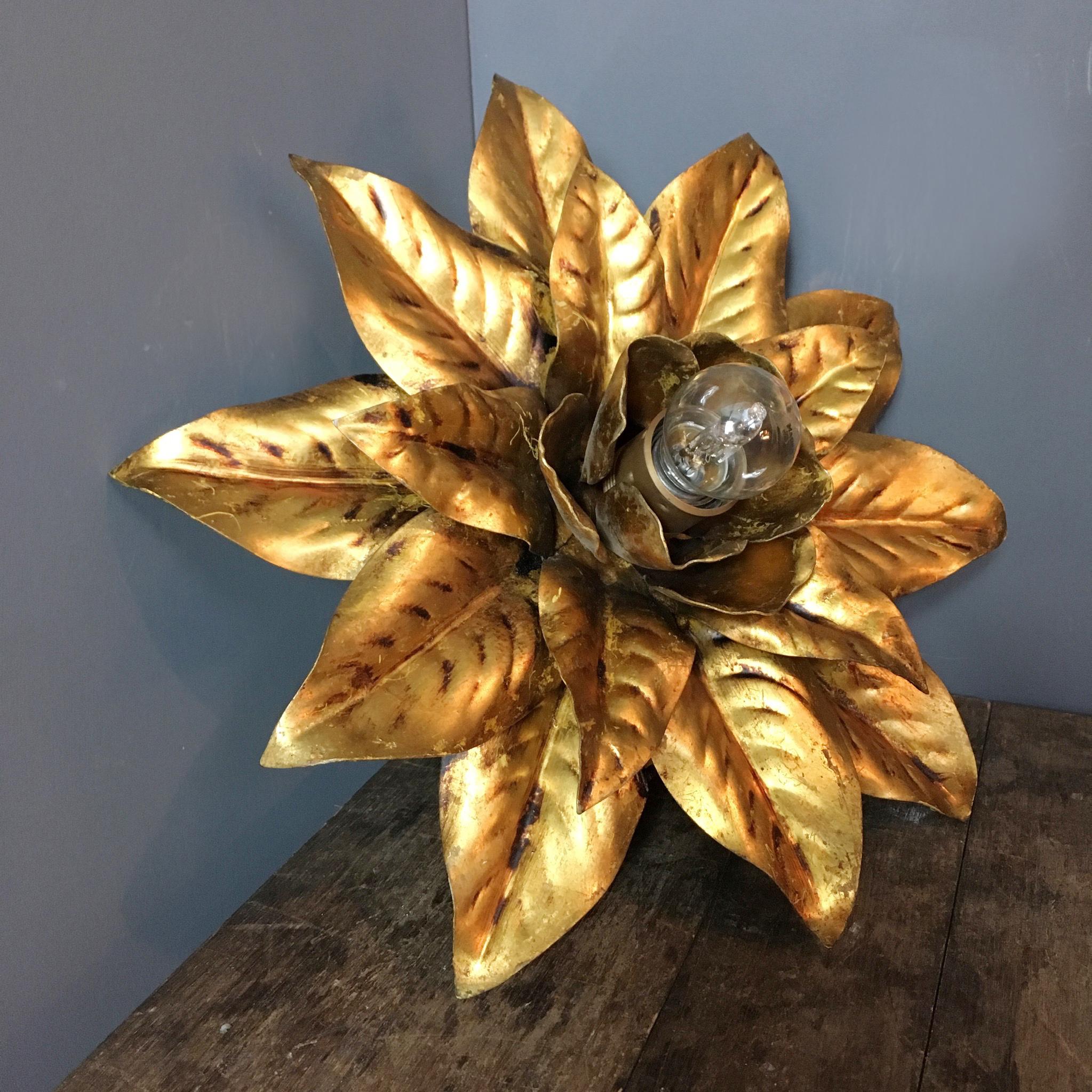 French gilt flower flush light

1970s 

Gilt metal with single E27 screw in centre bulb

The flower light hangs from a scalloped metal rose behind the petals

Measures: 36 cm width / height
13 cm depth (Total depth from ceiling including