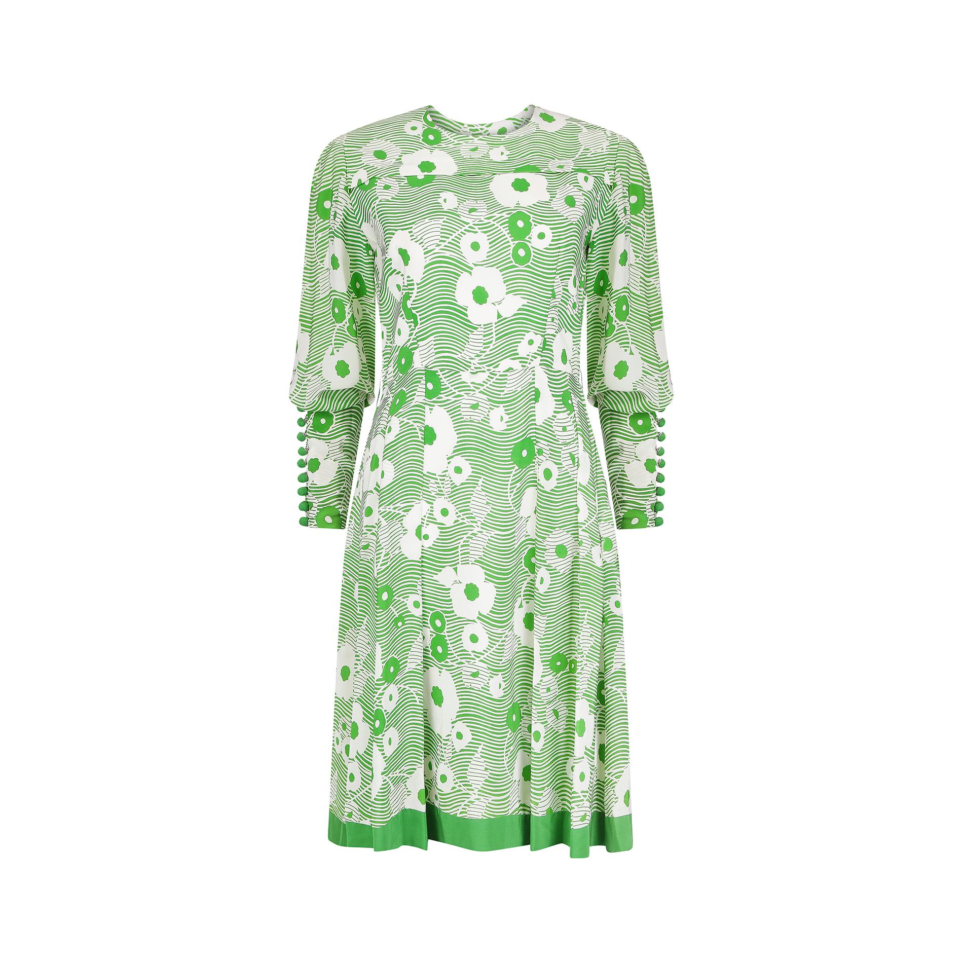 This 1970s French couture green and white dress in silk crepe features a striking floral fabric design. It has a softly rounded neckline and fastens down the back with an original white couture zip, complete with hook and eye fastening. The print