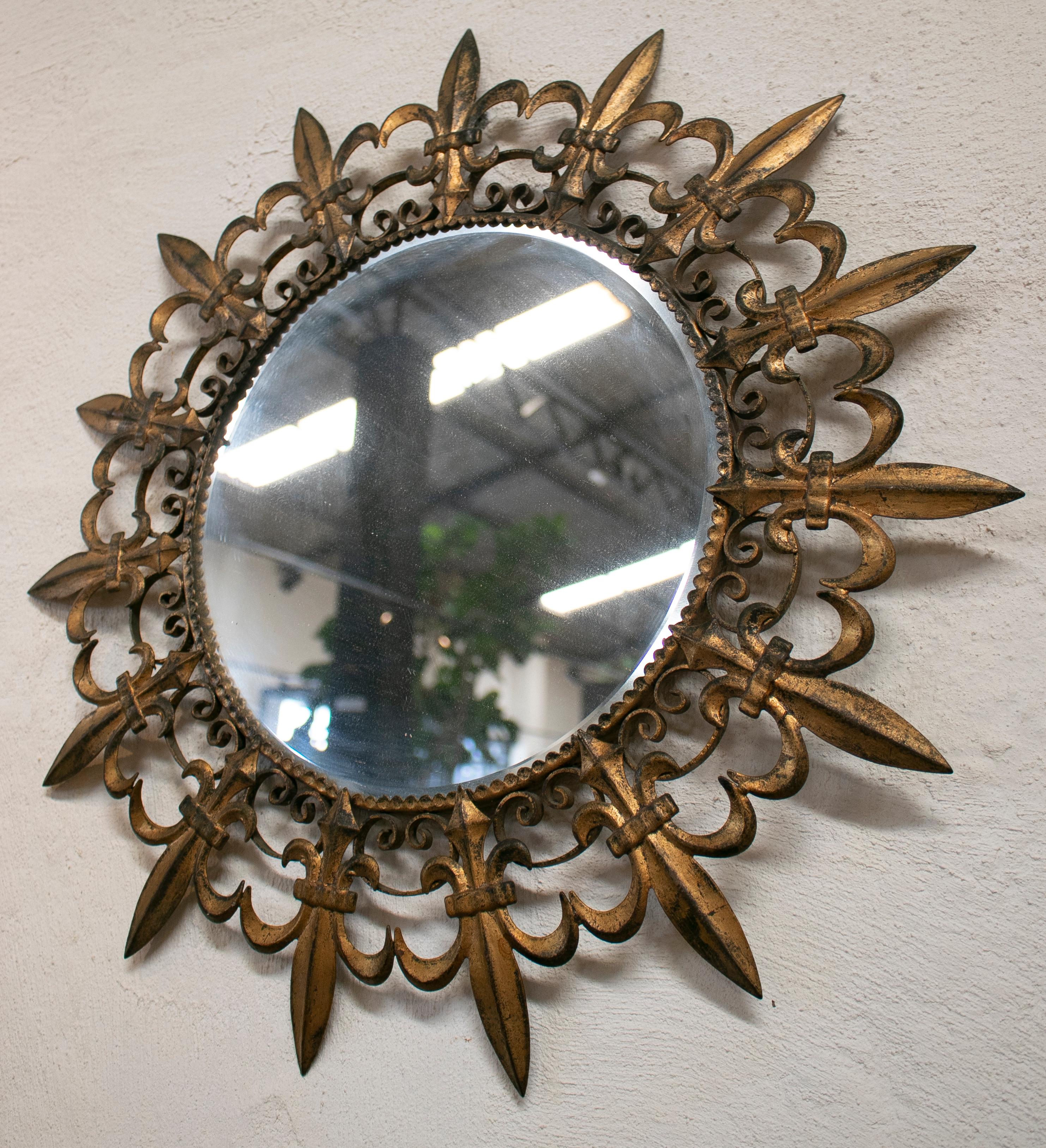 1970s French iron golden sun mirror with fleur-de-lis shaped bursts.