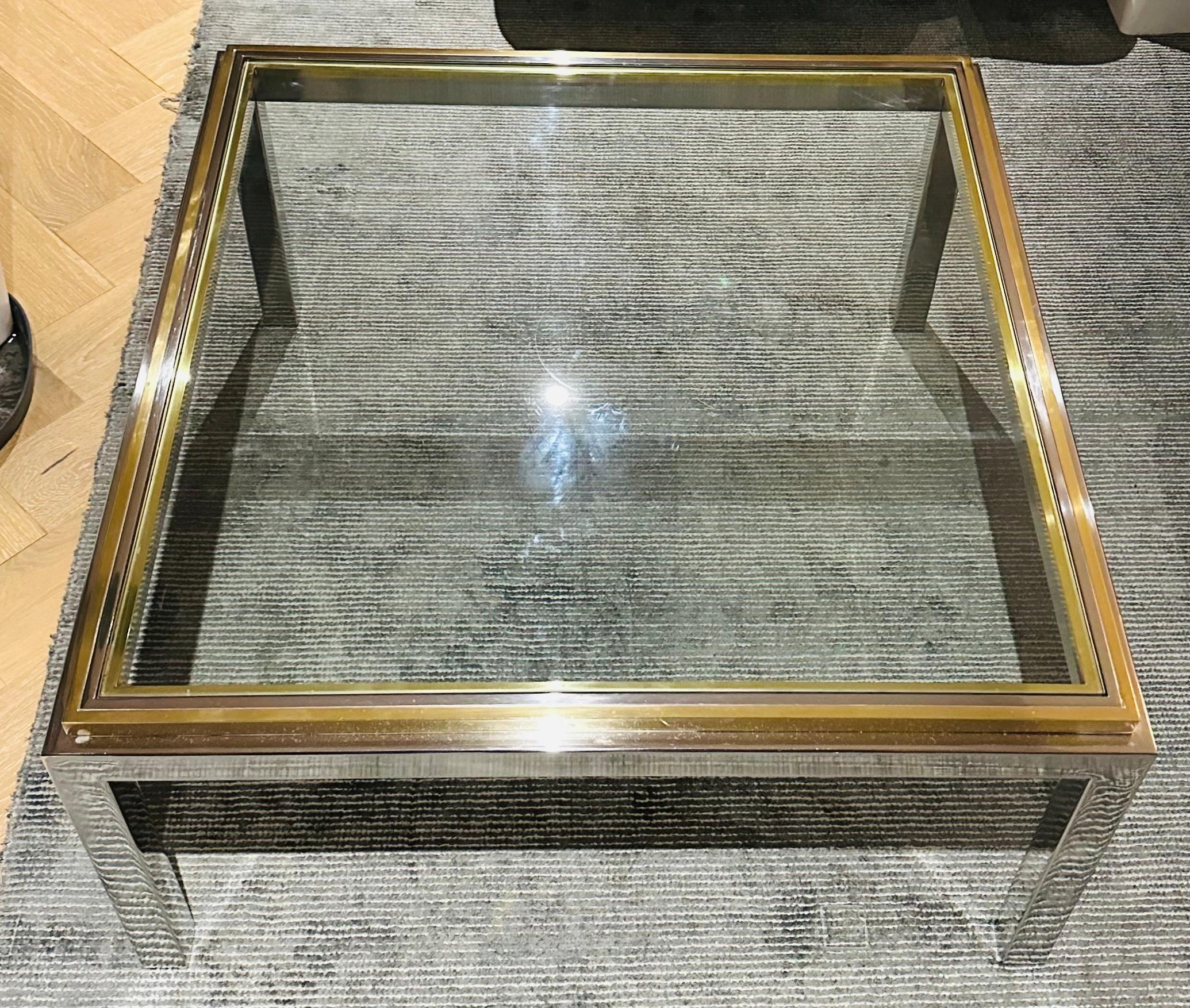 Table basse carrée en laiton et chrome de la Maison Jean Charles des années 1970. Le plateau est en verre transparent biseauté flottant dans un cadre en laiton et chrome poli.  Signé 