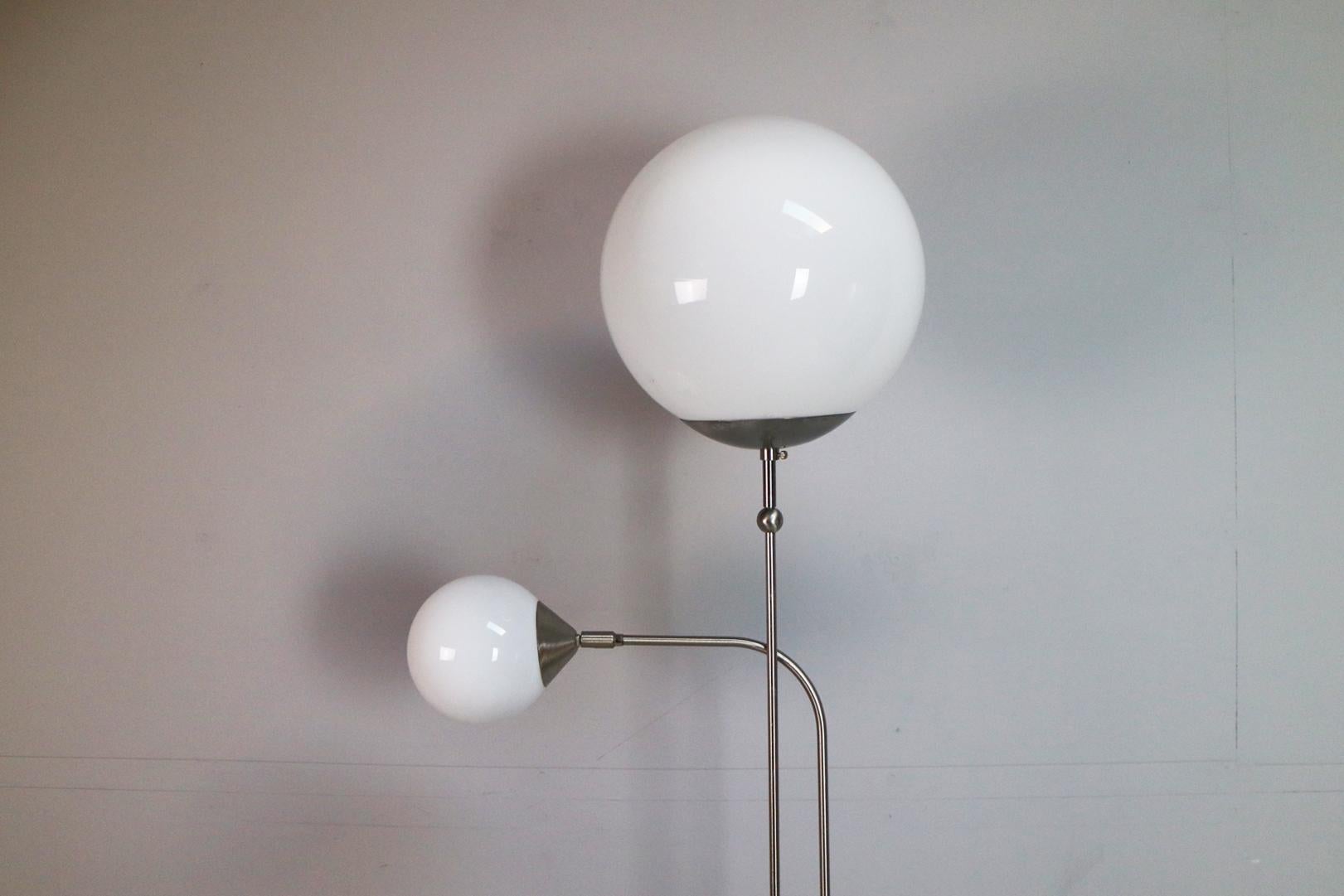 This is a lovely floor lamp with 2 white glass globes sitting on elegantly thin chromed steel rods. Very substantial and well made, the base is very heavy giving it good stability. The smaller globe is adjustable.
 