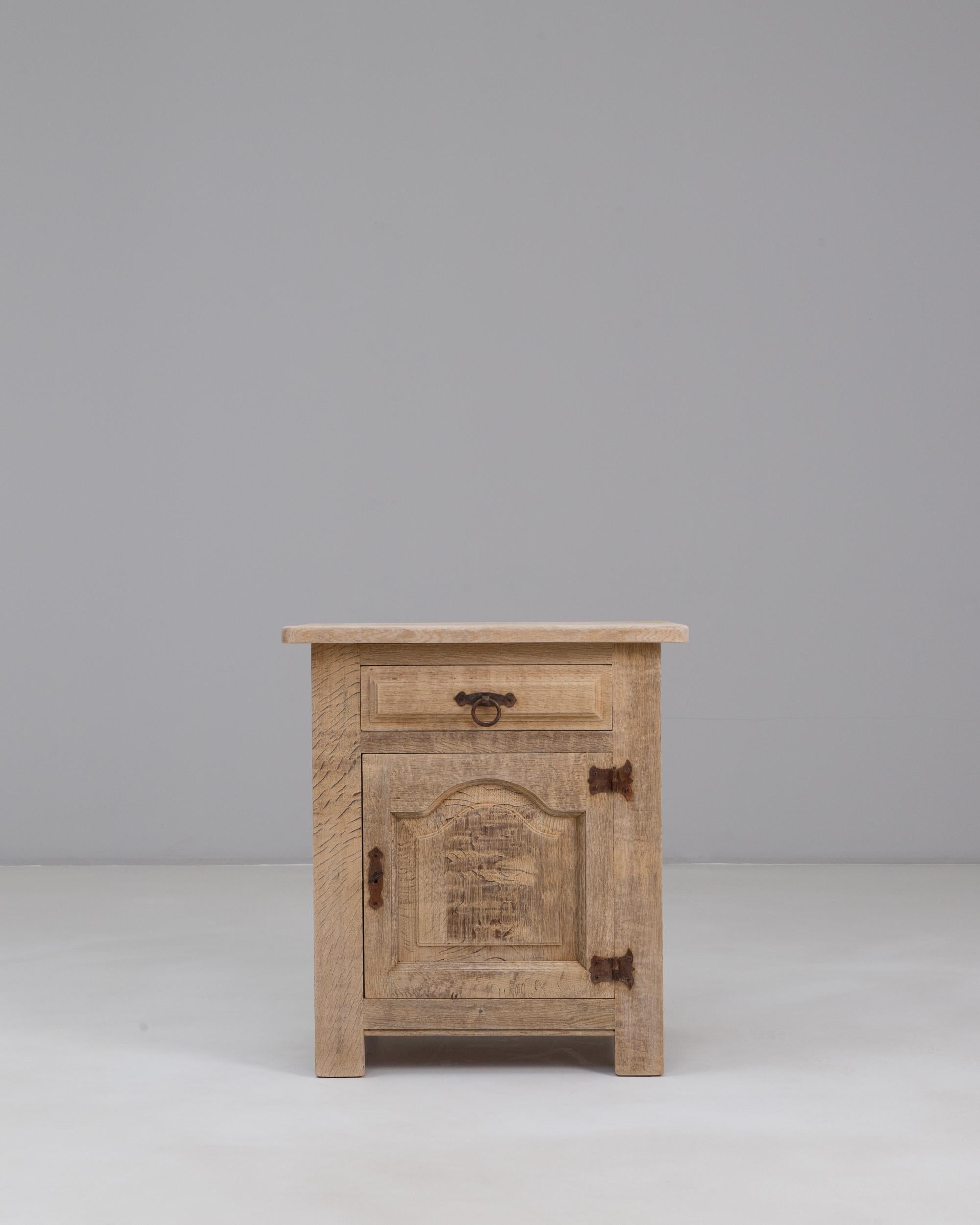 This 1970s French oak buffet combines rustic craftsmanship with a compact, highly functional design. Built from solid oak, it features a single paneled door with a gently arched motif that highlights the natural grain and texture of the wood. The