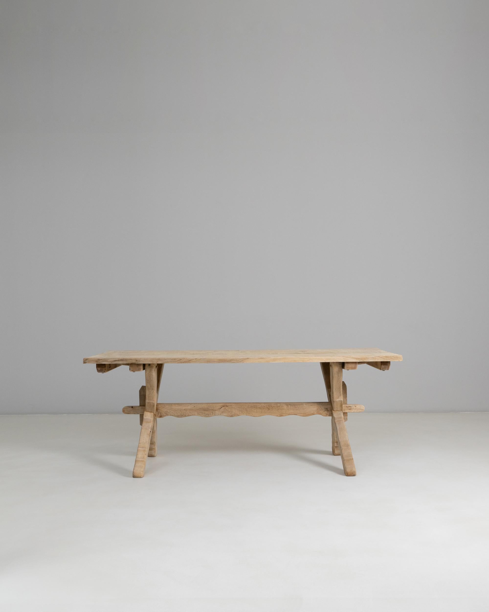 1970s French Oak Trestle Dining Table. This rustic trestle table from the 1970s is crafted from solid oak and features a soft, natural patina that highlights the wood’s grain and organic texture. Its sturdy construction is defined by splayed trestle