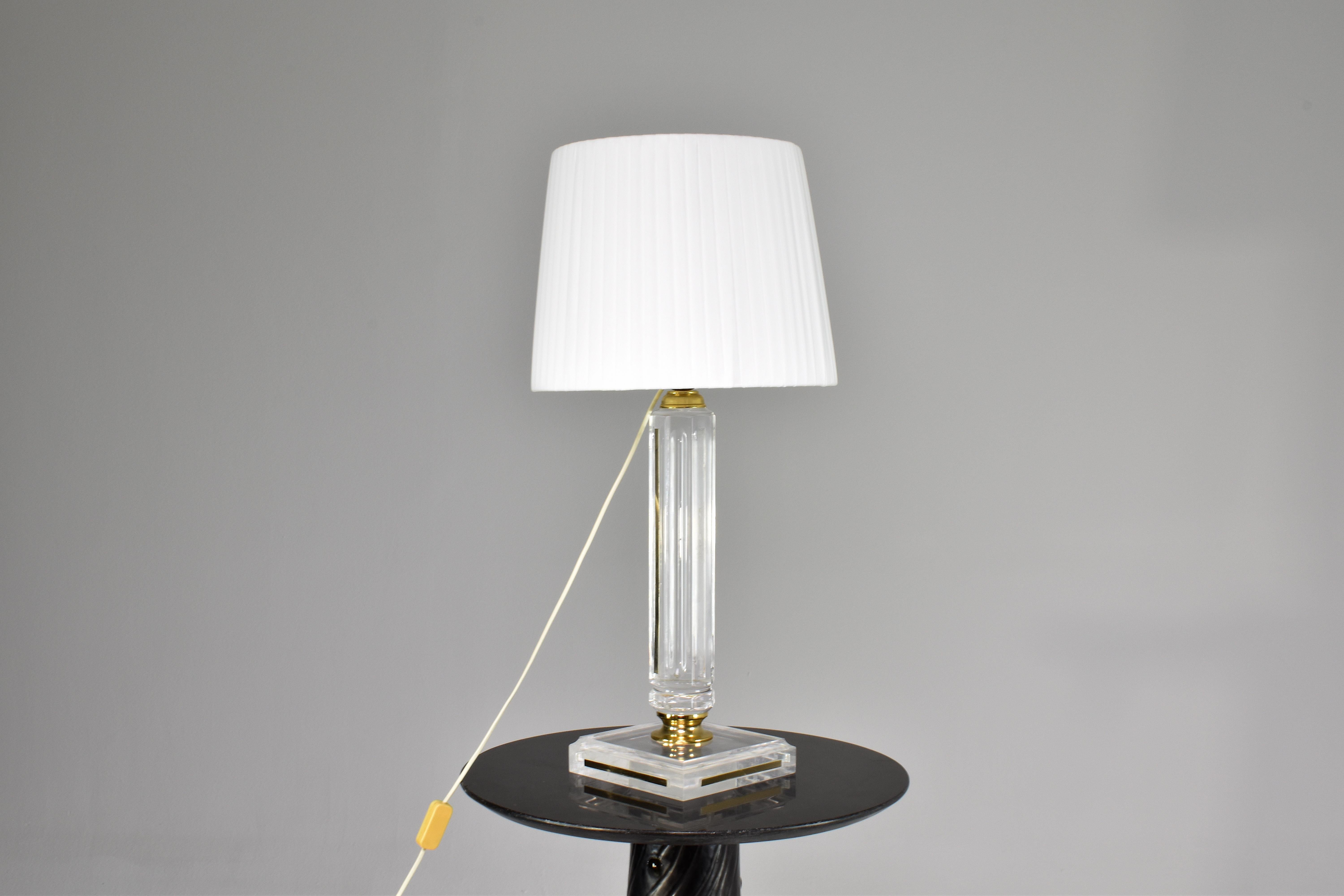 A superb tall French plexiglass table lamp in Hollywood Regency style with brass details. The transparency creates a beautiful interplay of light and form. Whether showcased atop a console table, or in a prominent spot in your living area, this