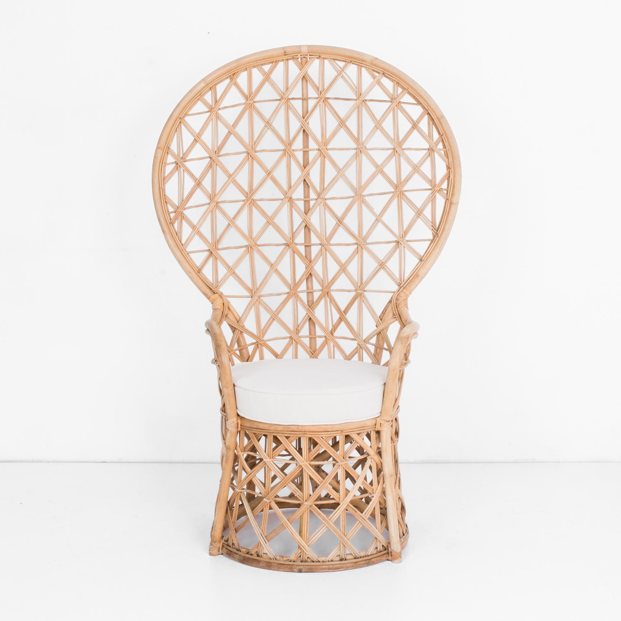 In typical mid-20th century rattan fashion, an “Emmanuelle” style armchair from circa 1950. This throne like chair has a great shape, with a thickly braided intriguing and supportive woven rattan back. Topped with a re-upholstered cotton-linen
