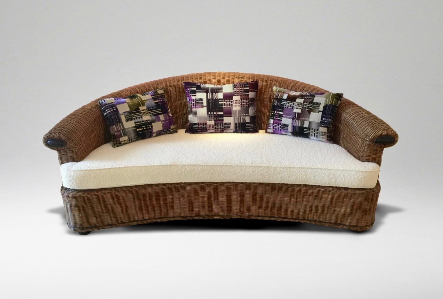 Very comfortable curved rattan sofa with rolled top edge, with re-upholstered seat cushion in off-white bouclé fabric and three back cushions in geometric velvet and metallic threads.
 