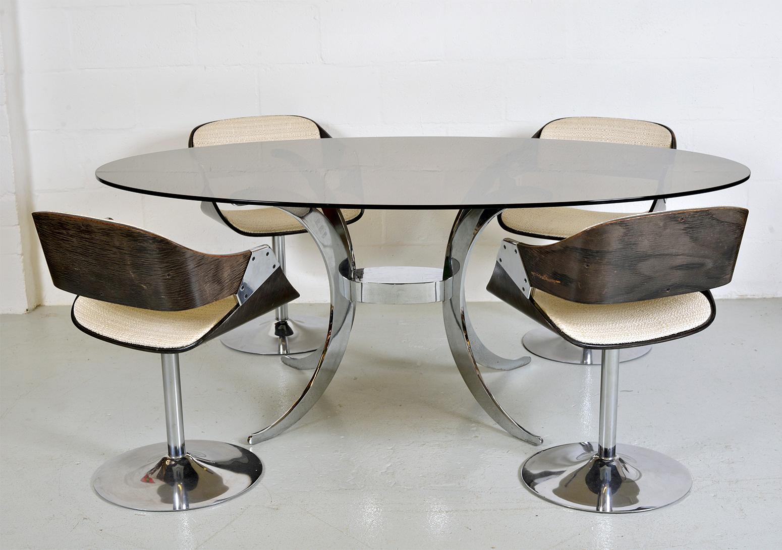 A seriously stylish 1970s Roche Bobois dining suite comprising of a table and four chairs bought from the south of France. An oval smoked glass top sits upon an elegant, and heavy-duty central chrome base, where four moon-shaped legs stem from a