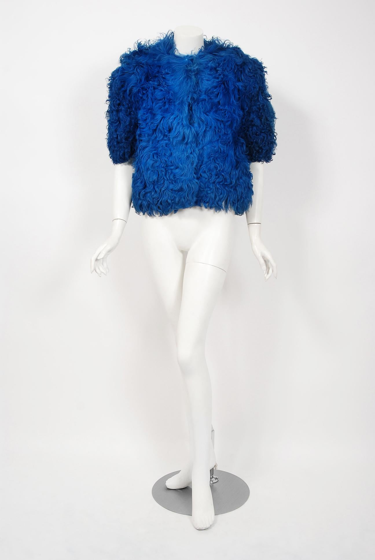 This exquisite 1970's Monsieur of Paris genuine curly-lamb bolero will make any woman shine during the colder months ahead. The luxurious Mongolian fur has been carefully dyed and the sapphire-blue color is really breathtaking. Chic cropped sleeves,