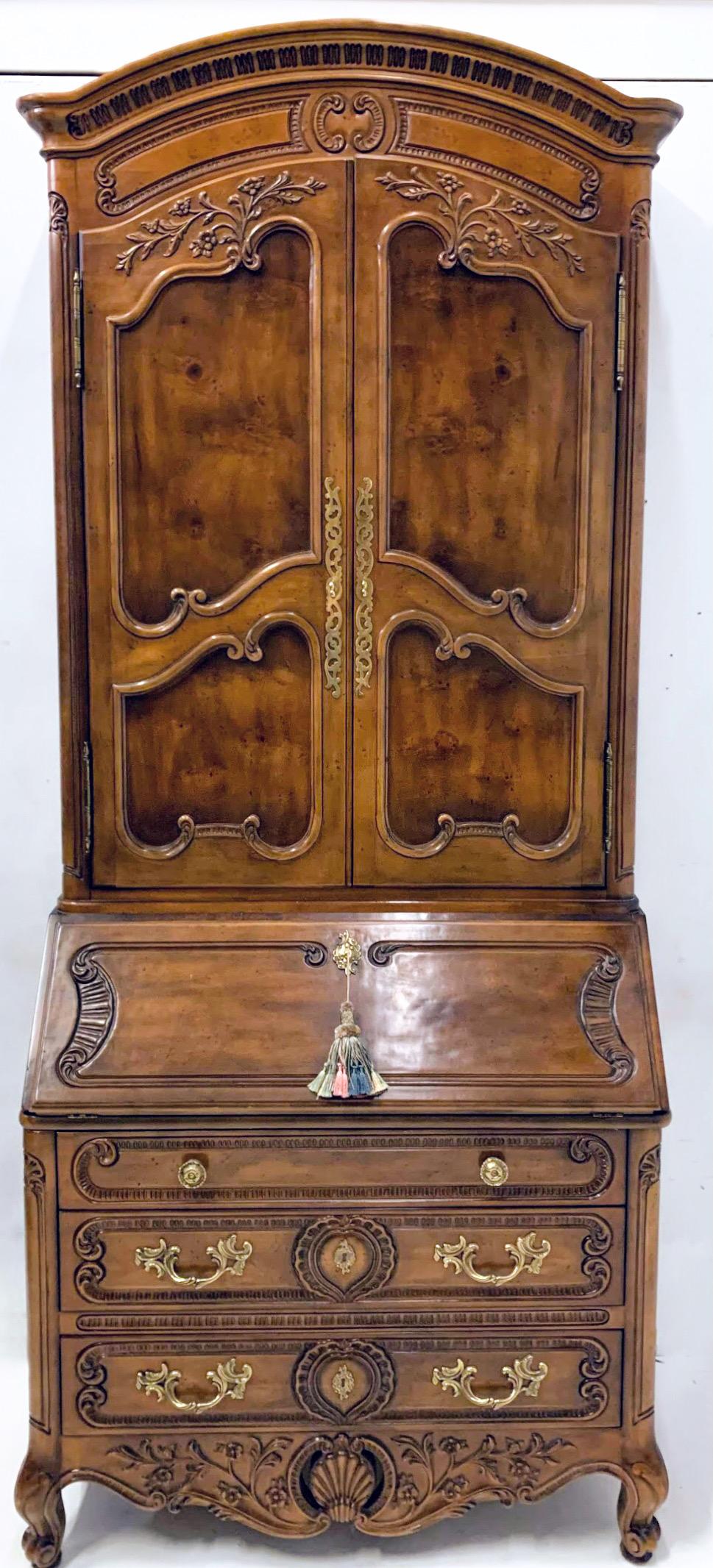 This is a lovely French style heavily carved burl walnut secretary by Henredon. The top half has two glass shelves and does light. It is in very good condition and is marked.