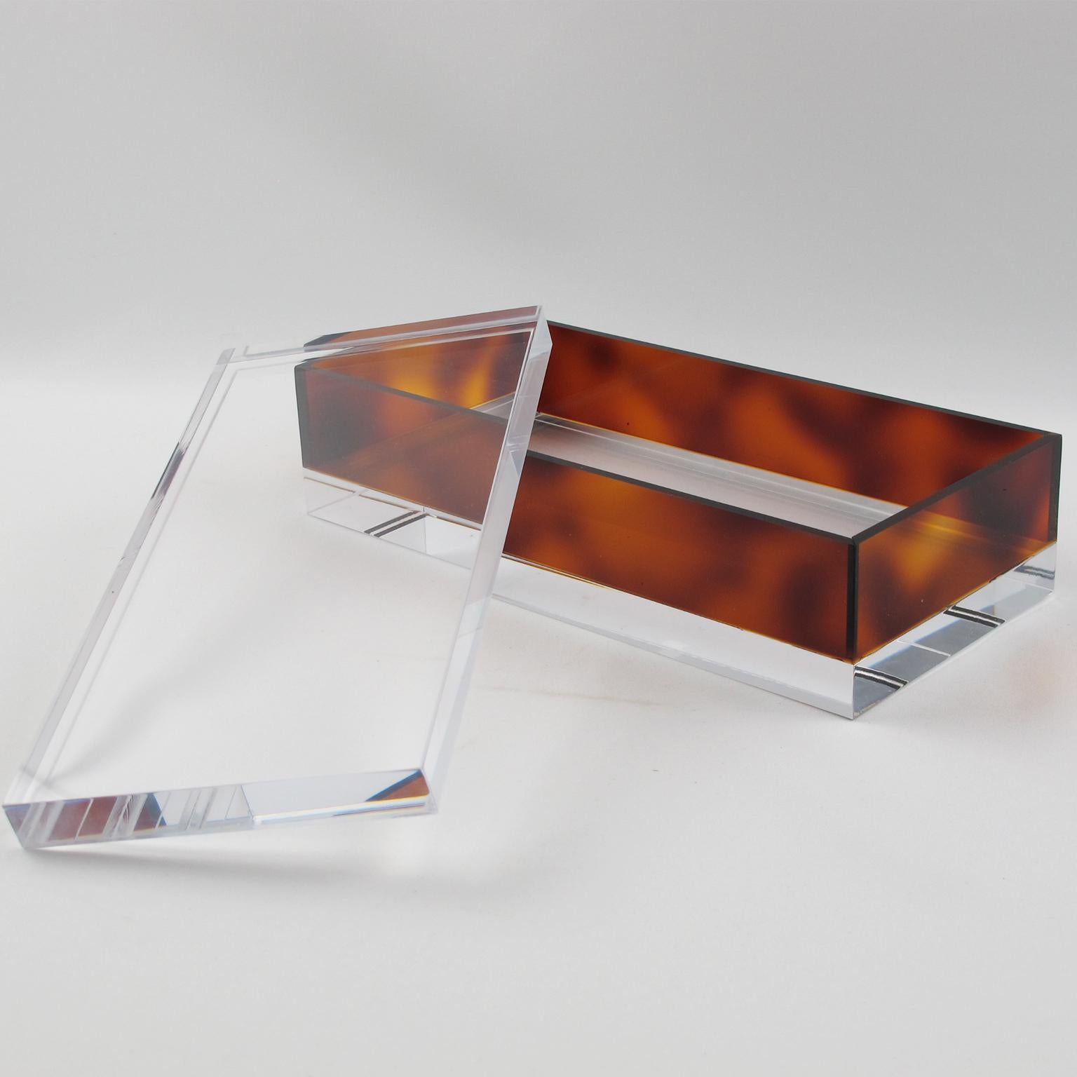 Stylish French 1970s modernist lidded box. Crystal clear and faux tortoiseshell (tortoise) color Lucite or plexiglass, long geometric rectangular shape. No visible maker's mark.
Measurements: 9.07 in. wide (23 cm) x 4.50 in. deep (11.5 cm) x 2.75