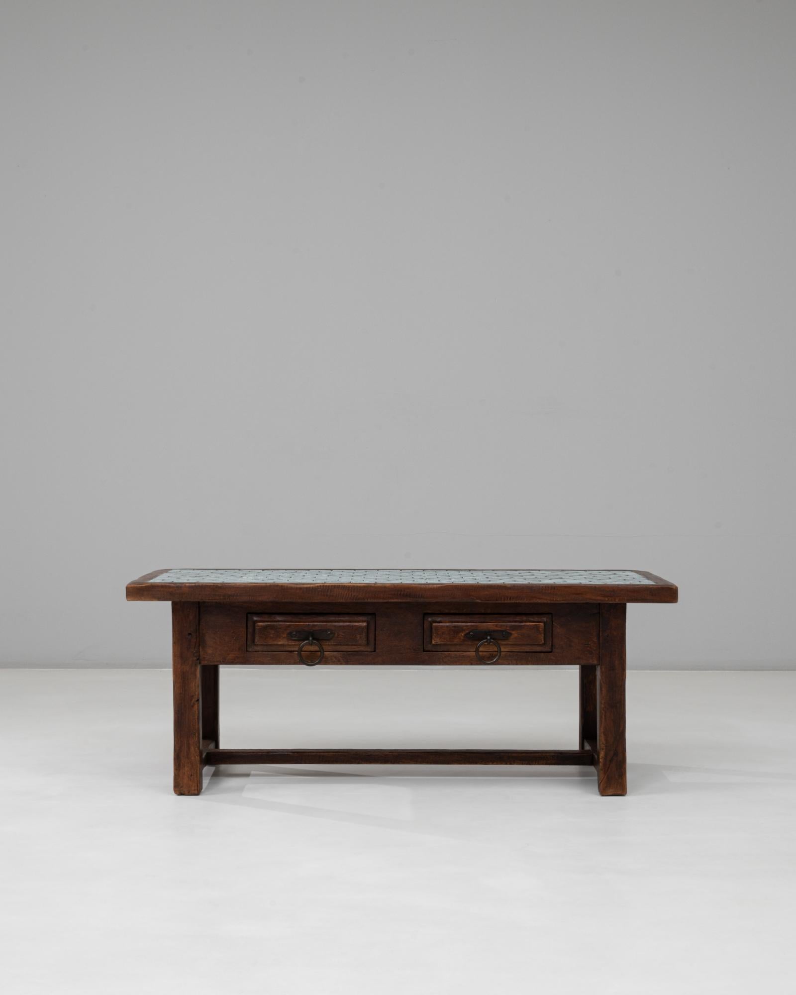 This 1970s French wooden coffee table showcases a stunning fusion of craftsmanship and color. The solid wood frame features clean lines and sturdy construction, while the top is inlaid with vibrant turquoise hexagonal tiles, creating a striking