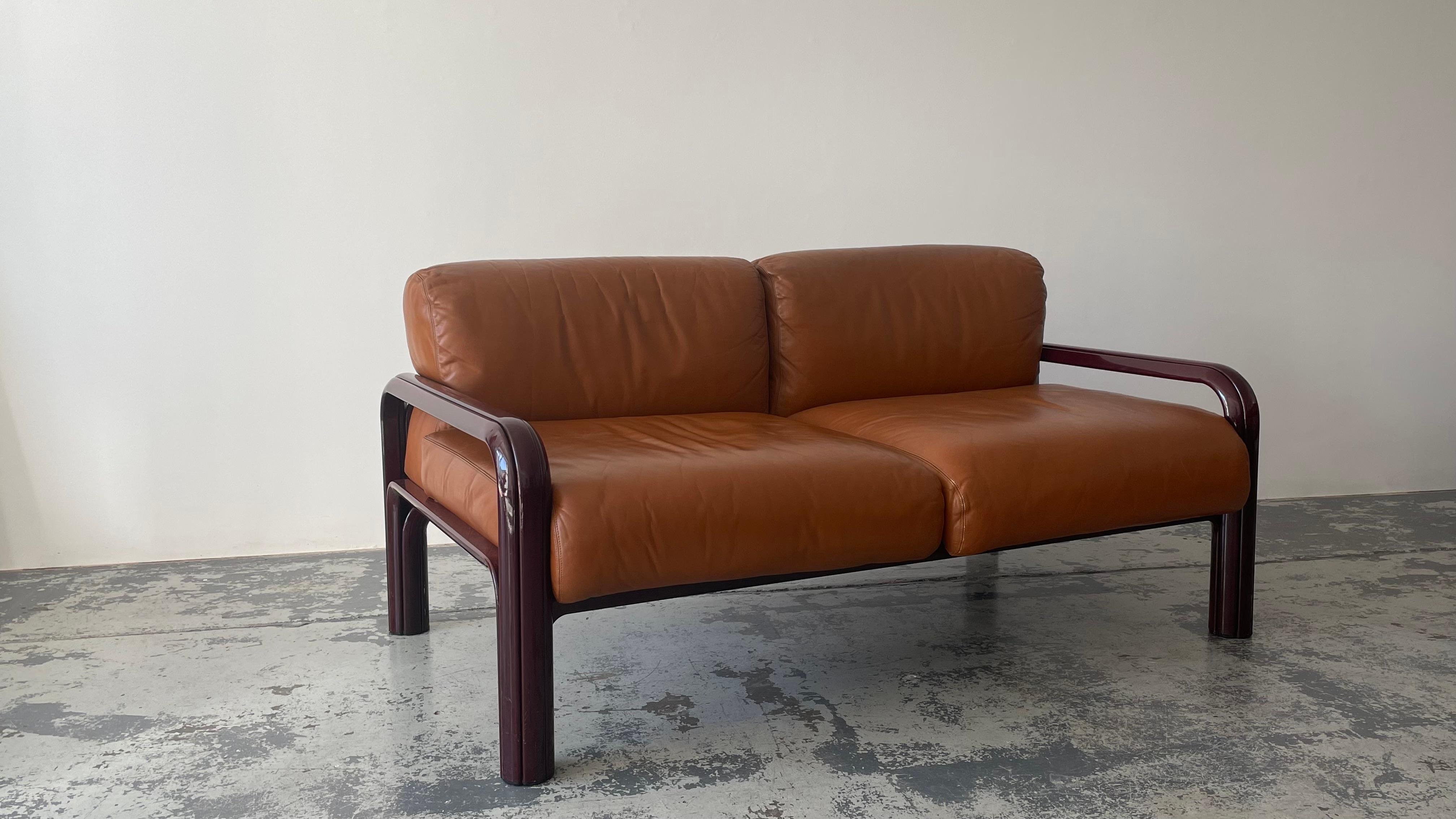 Two Seaters Sofa in cognac leather designed by Gae Aulenti in 1976 as part of the lounge seating line for the Aulenti Collection of Knoll International.

The lacquered burgundy frames are made from extruded steel.

The leather is in great