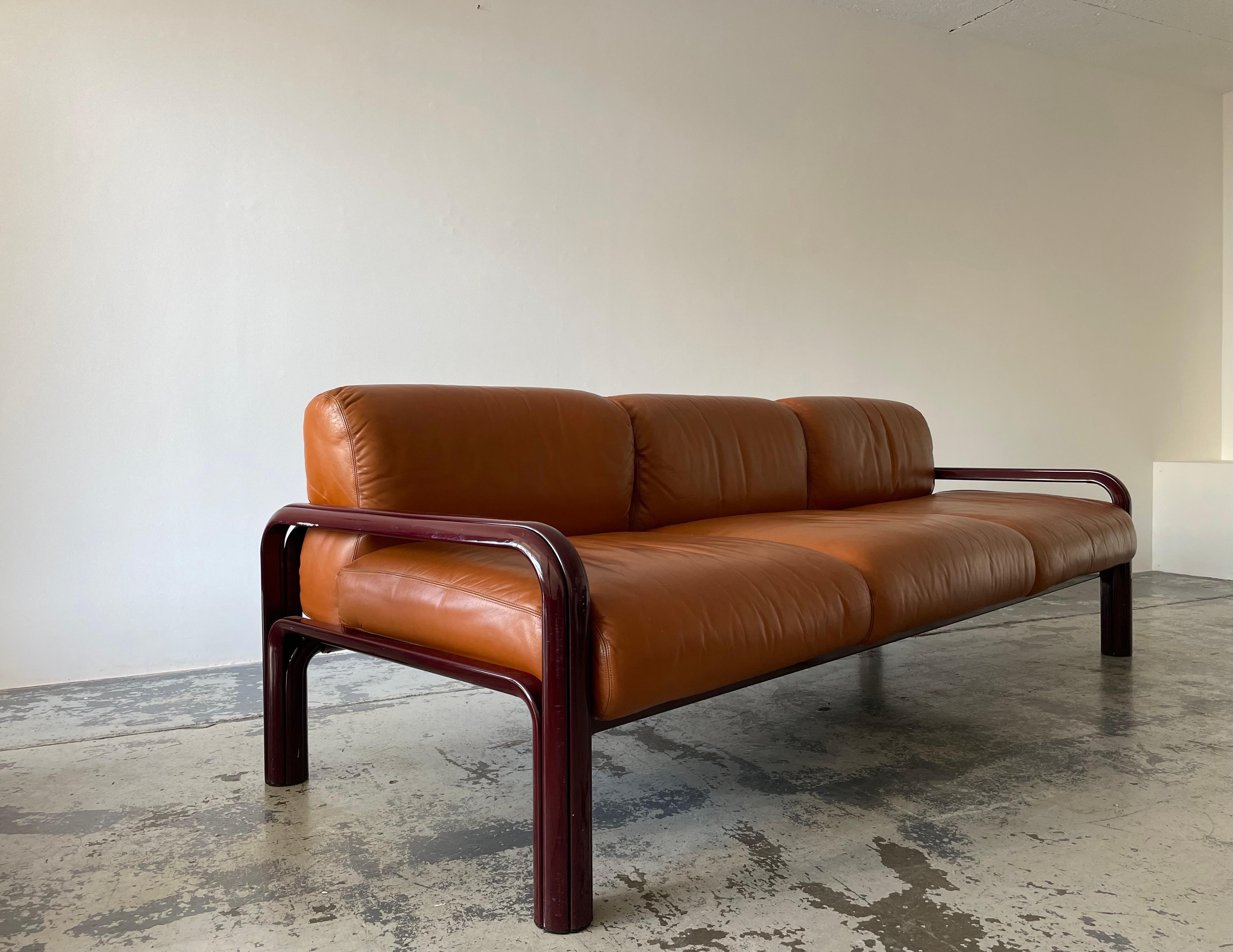Three seaters sofa in cognac leather designed by Gae Aulenti in 1976 as part of the lounge seating line for the Aulenti Collection of Knoll International.

The lacquered burgundy frames are made from extruded steel.

The leather is in great