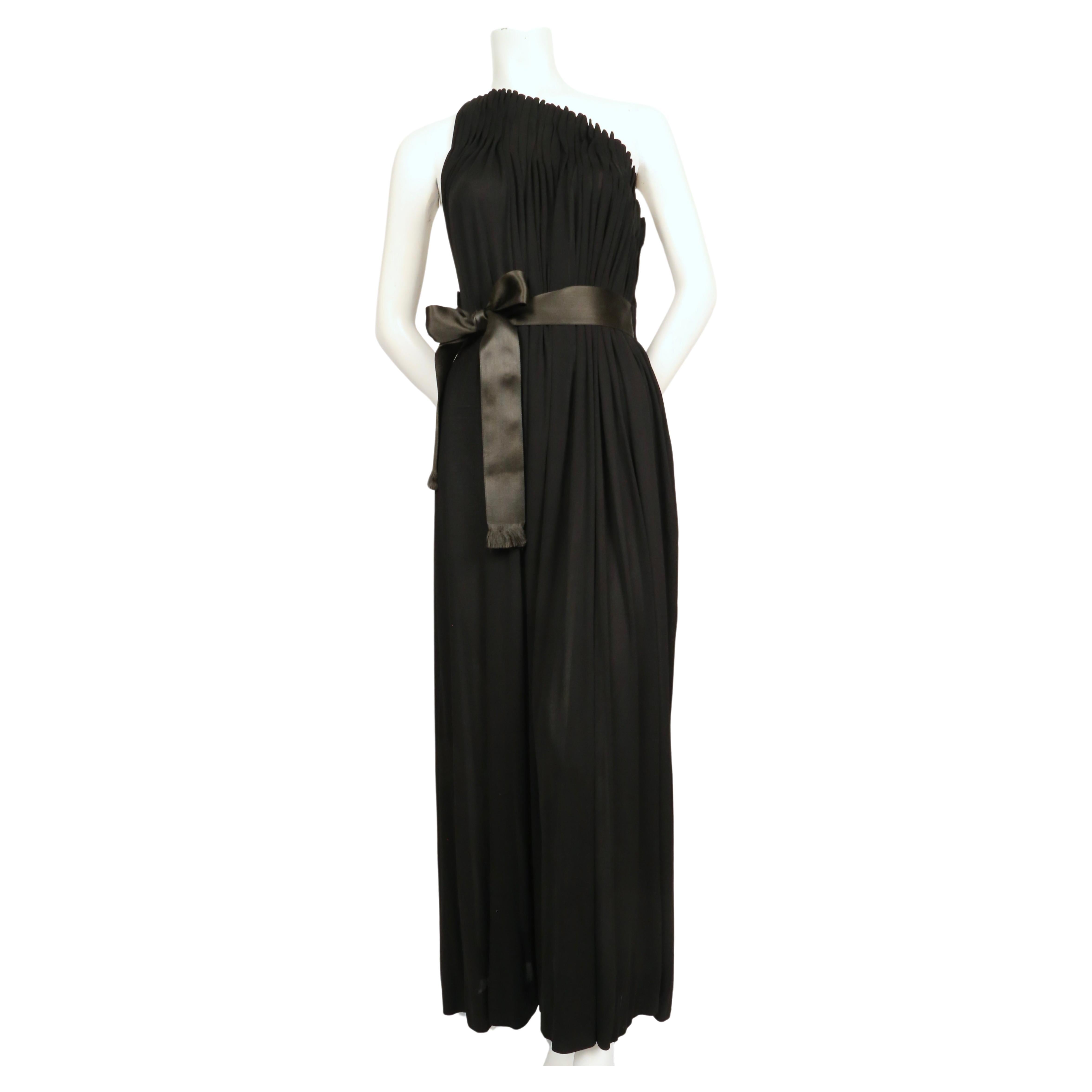Stunning jet-black, silk jersey gown with fluted box pleated bodice from James Galanos dating to the 1970's. Dress has a very strong silhouette with a very unique asymmetrical high neckline with a single thin strap at back.  On either side of the