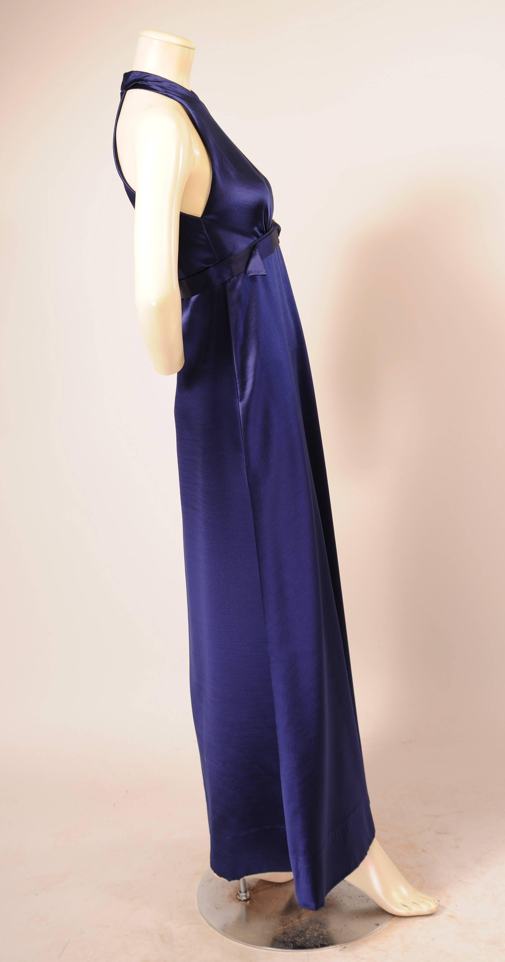 Sapphire blue silk satin is perfect for this sleek evening dress designed by James Galanos in the 1970's. The round neckline and cut in armholes create a clean modern look, accented by the slightly raised waistline with silver ring trim. The dress