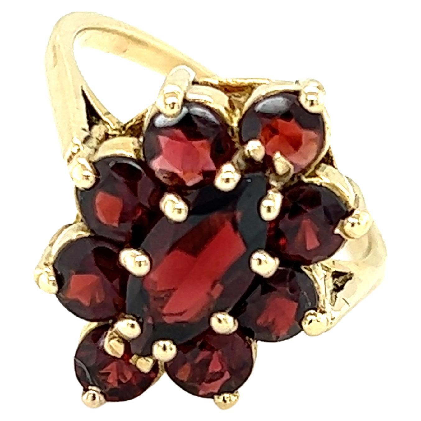 One 14 karat yellow gold ring set with one (1) 10x5mm marquise-shaped red garnet, surrounded by a cluster of eight (8) 3.5mm round red garnets. The ring is a finger size 6.75 and is resizable.  Sizing not included.  
