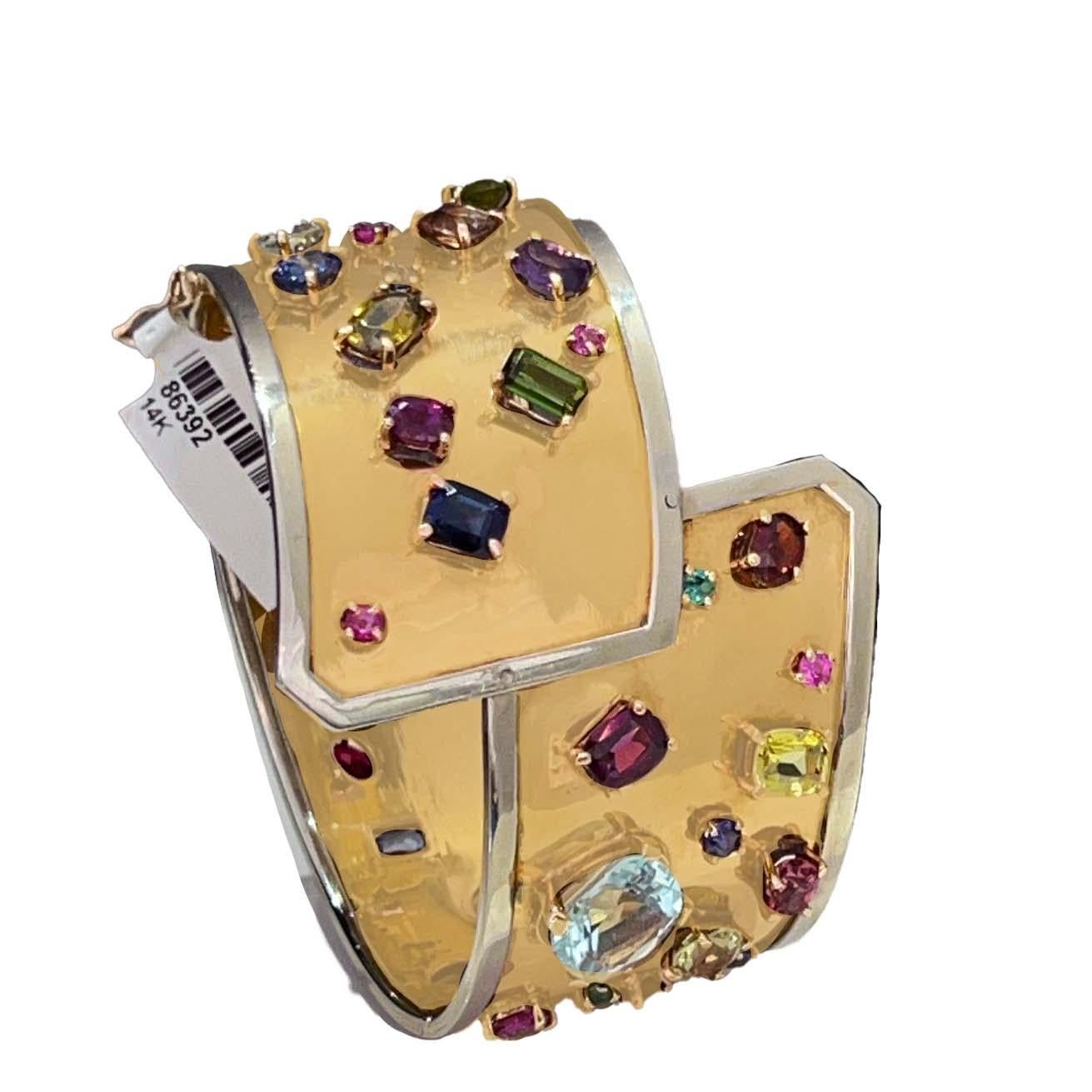 This 1970s 14 karat yellow gold multicolor semi precious gemstone cuff bracelet. Featuring a captivating wraparound yellow gold motif adorned with vibrant gemstones, creating a dynamic and eye-catching look. The border of the bracelet surrounds the