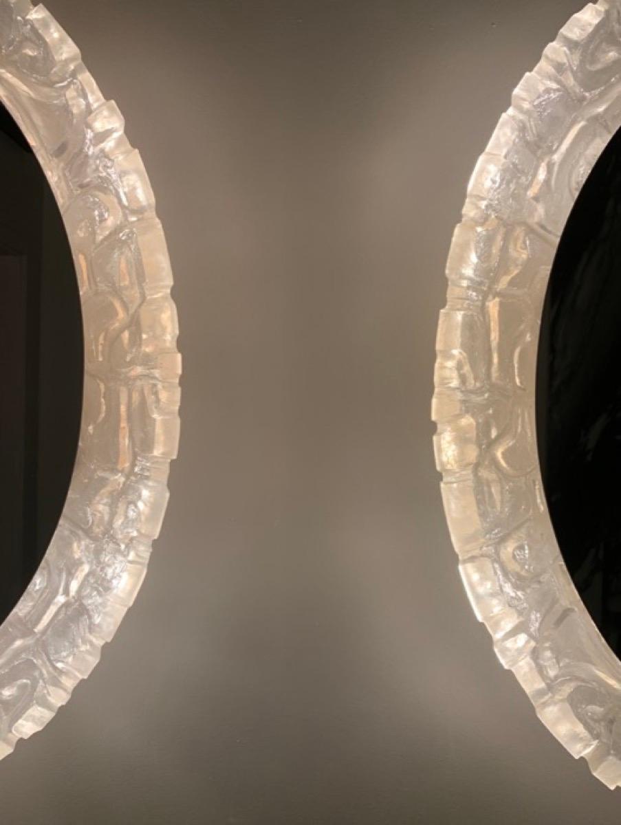 German lucite illuminated oval wall mirror. Manufactured by Erco in the 1970s.  The oval glass mirror sits within an unusual abstract, sculpted and textured molded frame which reflects the light throughout giving a warm and ambient glow. The mirror