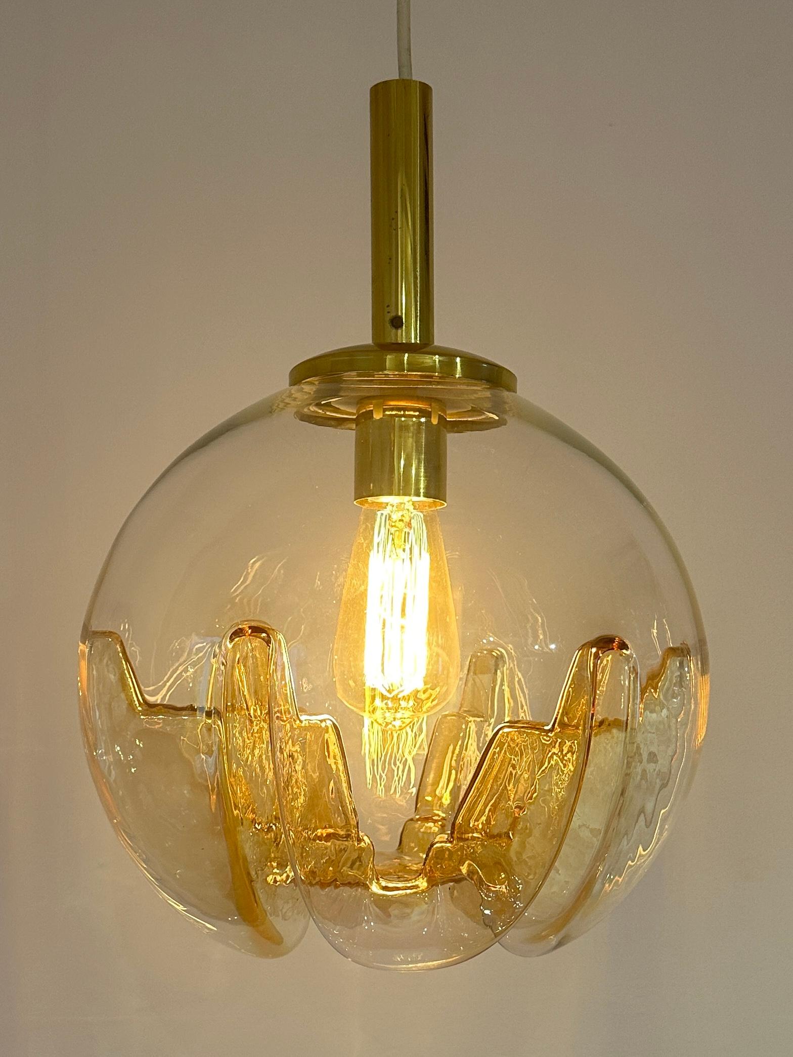 A stunning space-age, futuristic, 1970s German Doria Leuchten amber glass & brass globe hanging ceiling light.  The clear glass has a hint of amber which is more pronounced where the six lightening inclusions occur around the bottom half of the